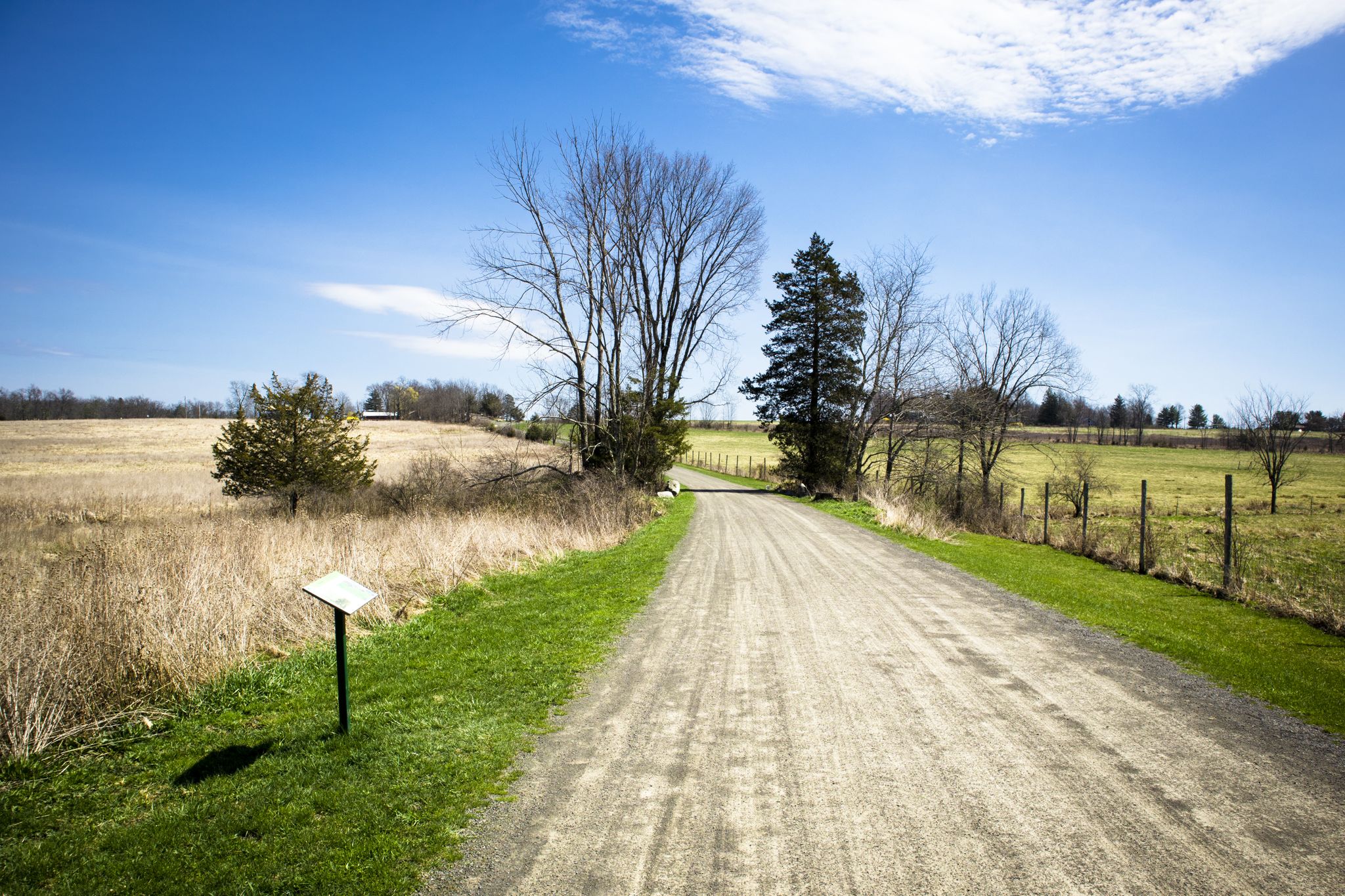 A dirt road winds through dry fields under a bright blue sky. - River-to-Ridge Trail