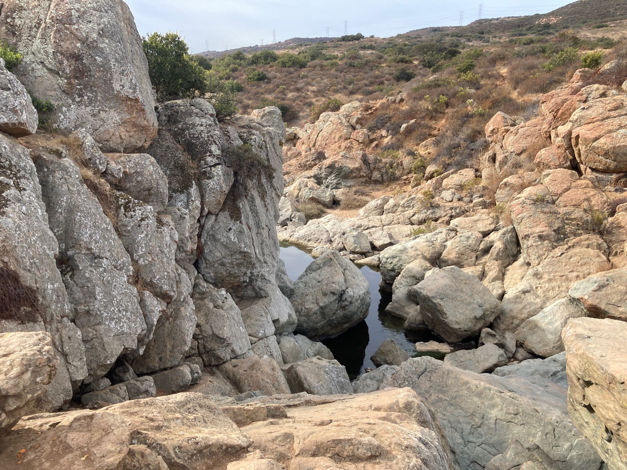 A rocky gorge with large boulders and small pools of water. Bright daylight. - Los Penasquitos Canyon Trail
