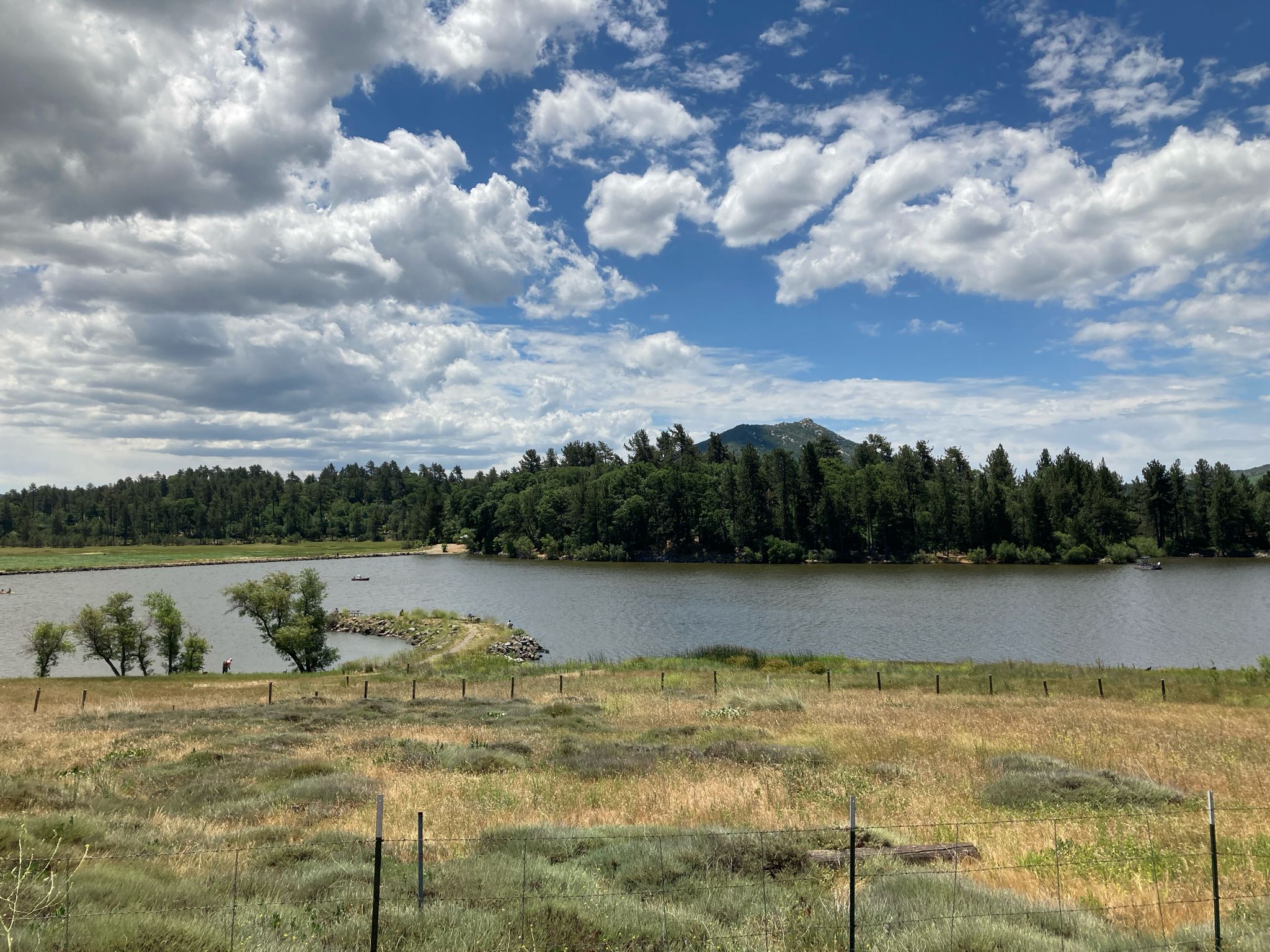 Wide lake with green trees and distant mountains under a cloudy blue sky. - Storm Canyon Overlook – Kwaaymii Point loop from Pine Valley