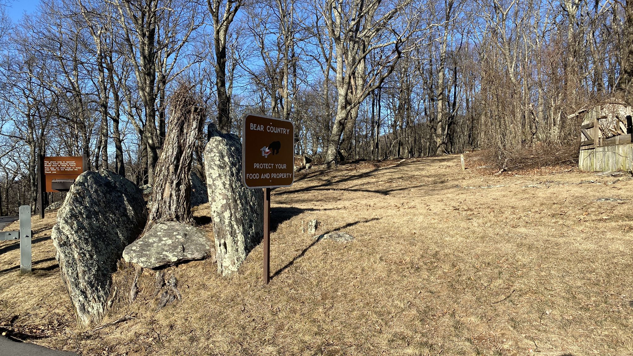 Bear warning sign near large rocks and bare trees on a dry hillside. - Rocky Knob Recreation Area & Campground loop