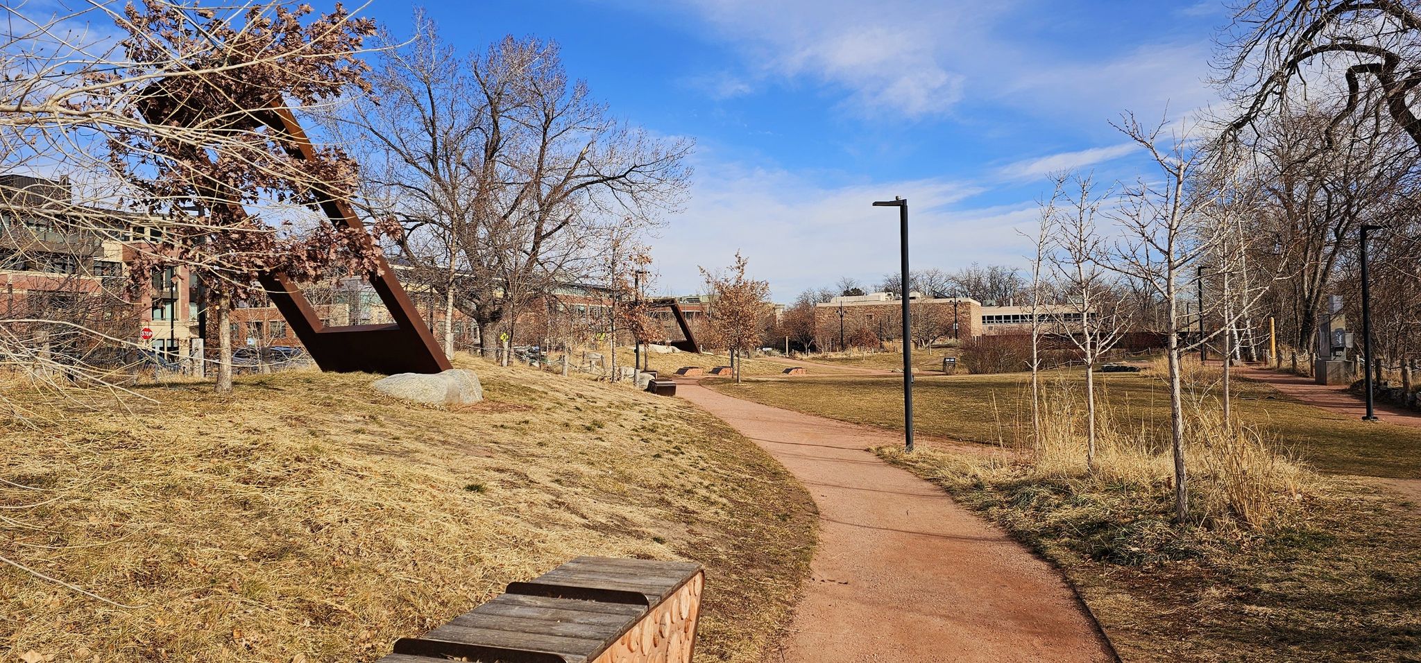 A winding dirt path through a park with bare trees and distant buildings. - Spruce Confections – Maxwell Reservoir loop from Boulder