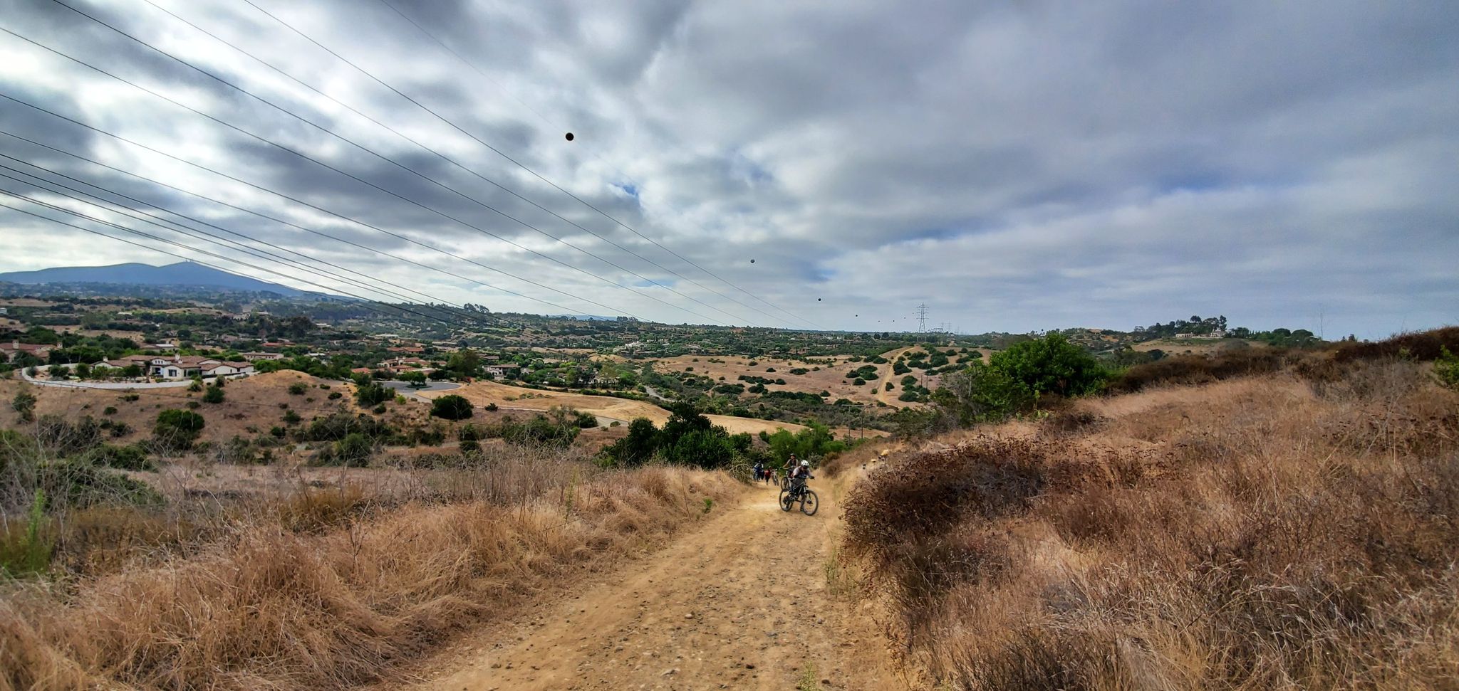 Cyclists on a dirt path through dry, hilly landscape under cloudy skies. - Gravel loop from Intuit Inc.