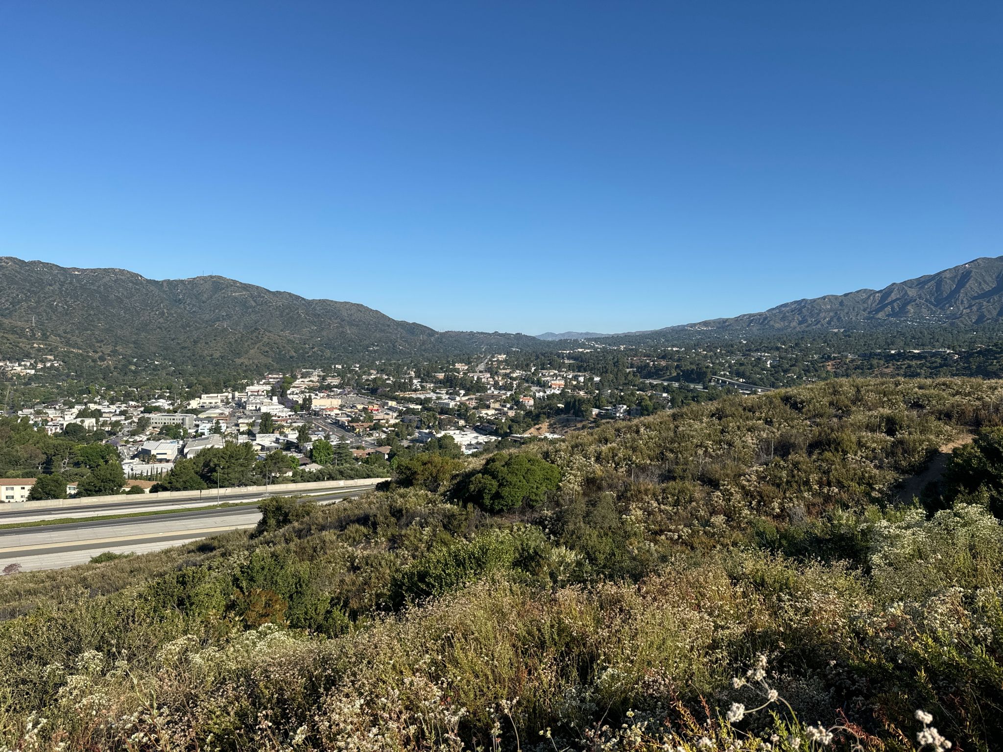 Expansive view of a town and highway nestled between green hills and mountains. - Cherry Canyon Park and Lookout Tower