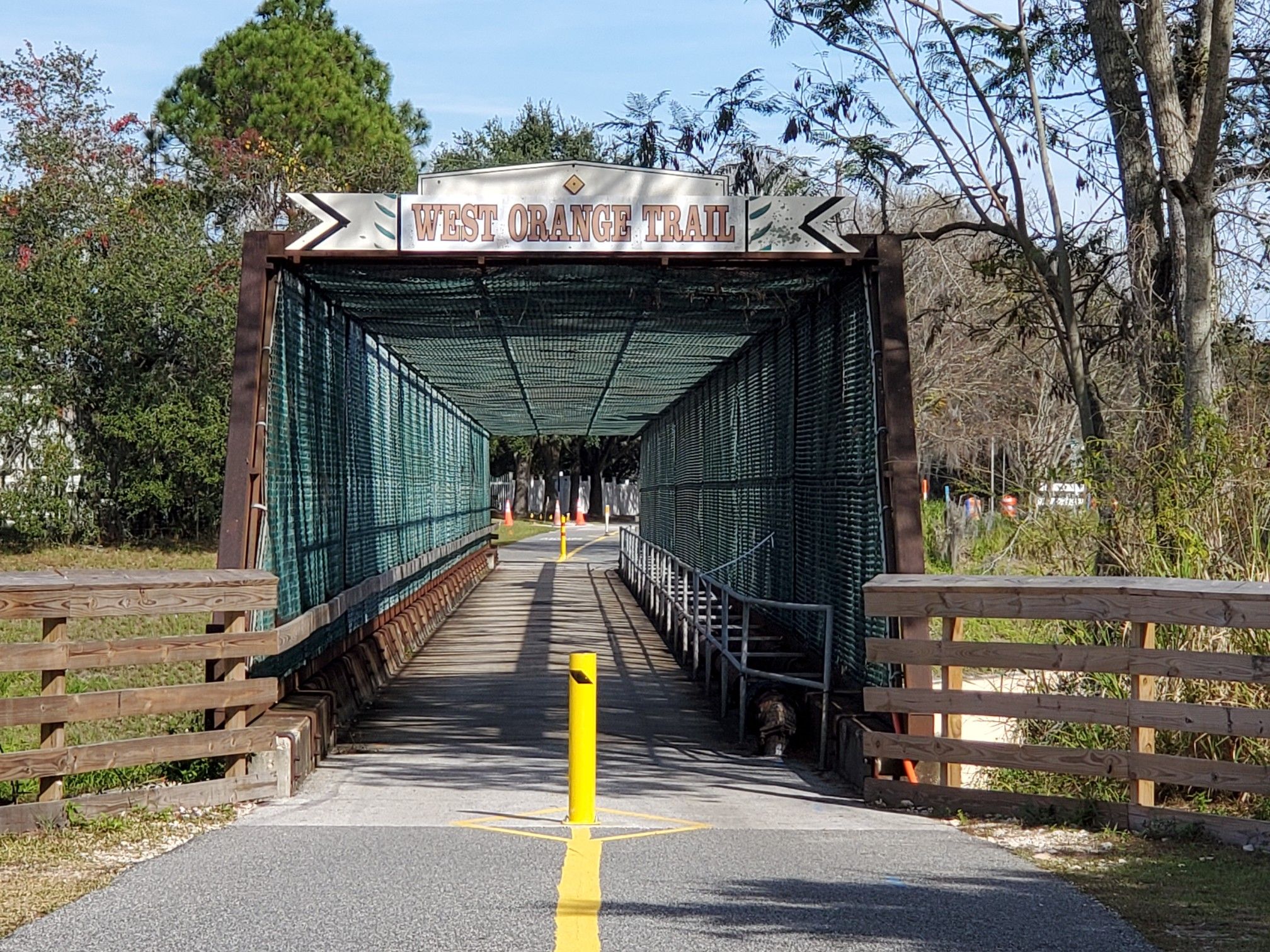 Sunny day with a covered pedestrian bridge over a paved path. - West Orange Trail – Sugarloaf Mountain Road loop from Winter Garden