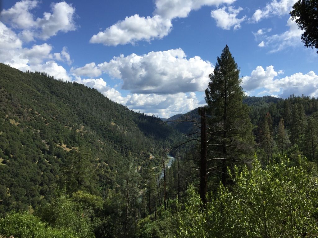 Lush green mountain valley with a river under a partly cloudy sky. - Stevens Trail