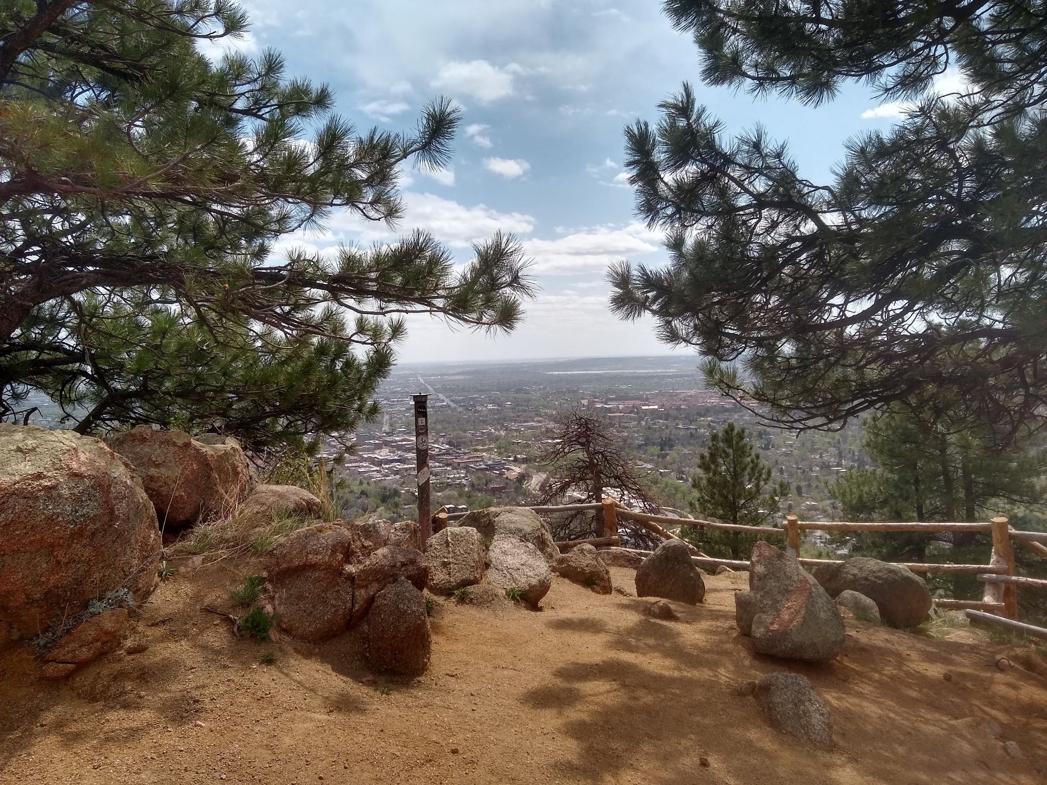 Pine trees and rocks frame a view of a city in a valley. - Red Rocks and Anemone Loop