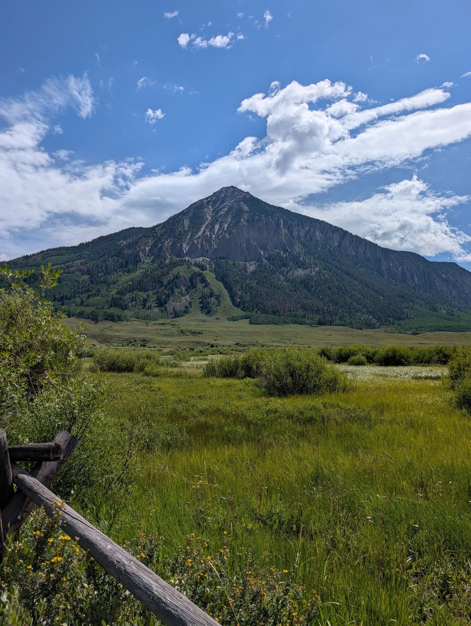 Majestic mountain overlooking a vast green meadow under a blue sky. - Crested Butte Downtown loop from Upper Loop
