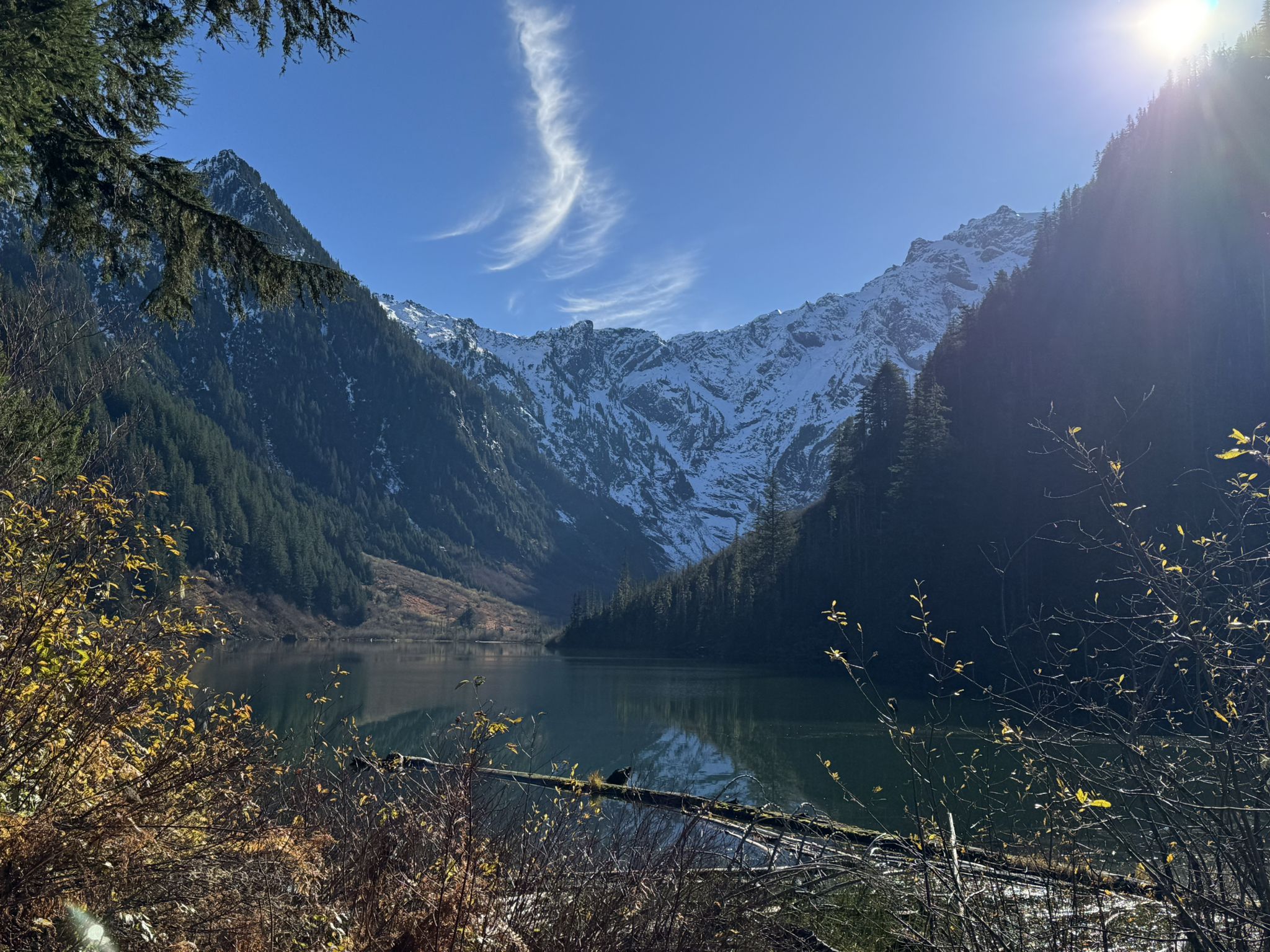 Sunny mountain lake with snow-capped peaks and green forests reflecting. - Elliot Creek (Goat Lake) Trail