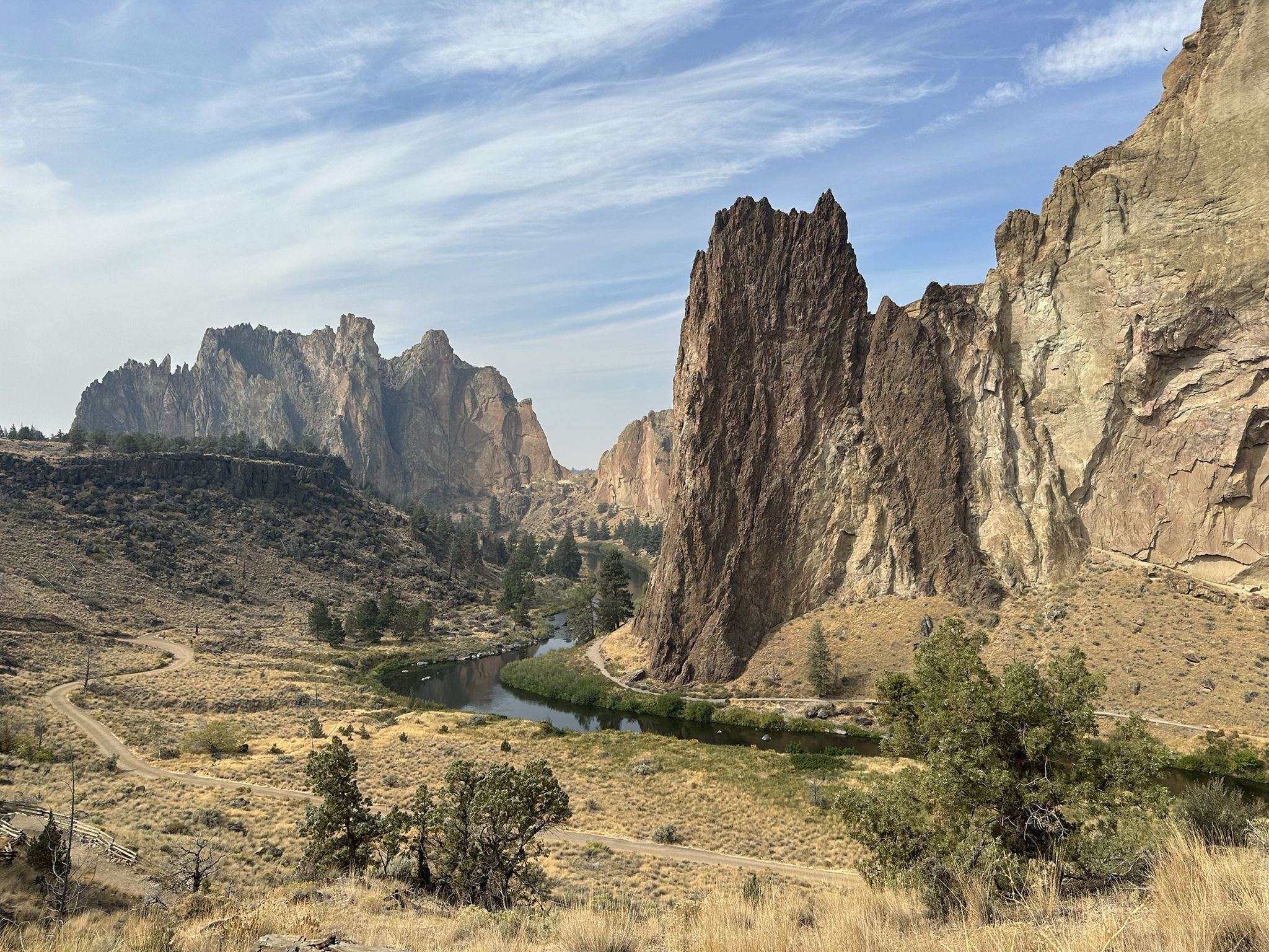 River winds through a canyon with towering rock formations under a partly cloudy sky. - Misery Ridge and River Trail Loop