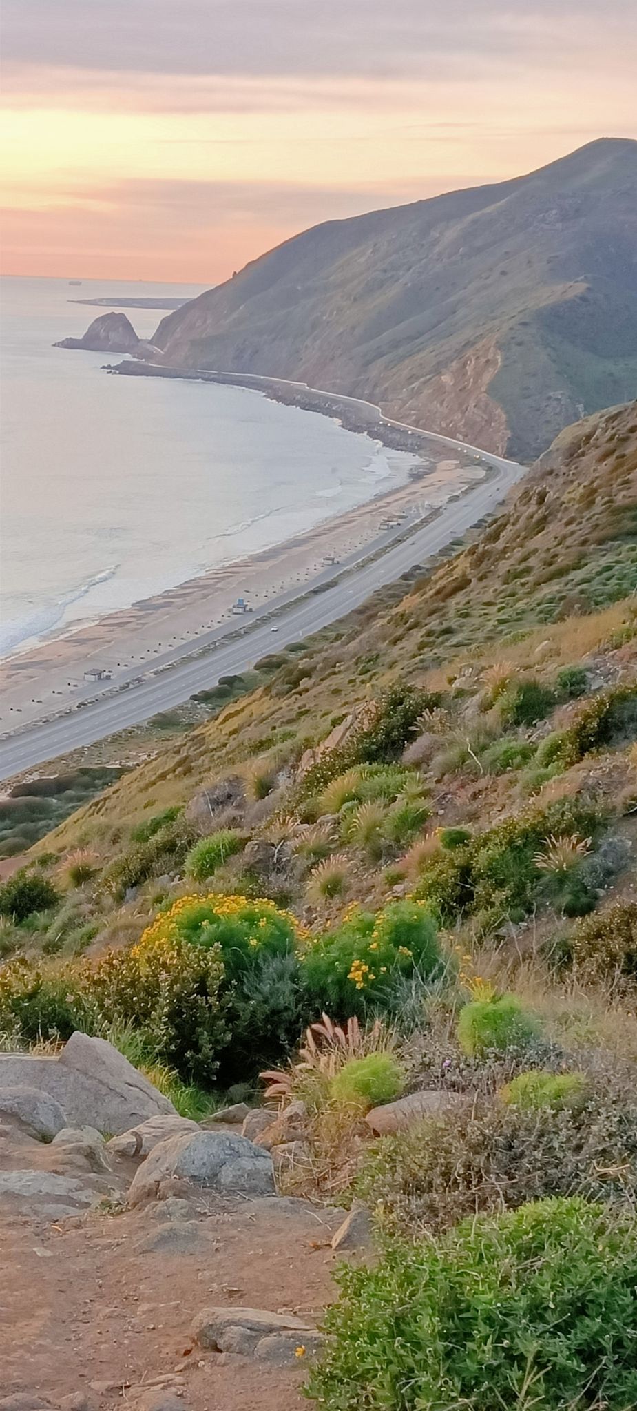 Coastal mountains, a winding road, and beach under a soft sunset sky. - Point Mugu Beach Overlook – Old Boney Trail loop from Sycamore Cove