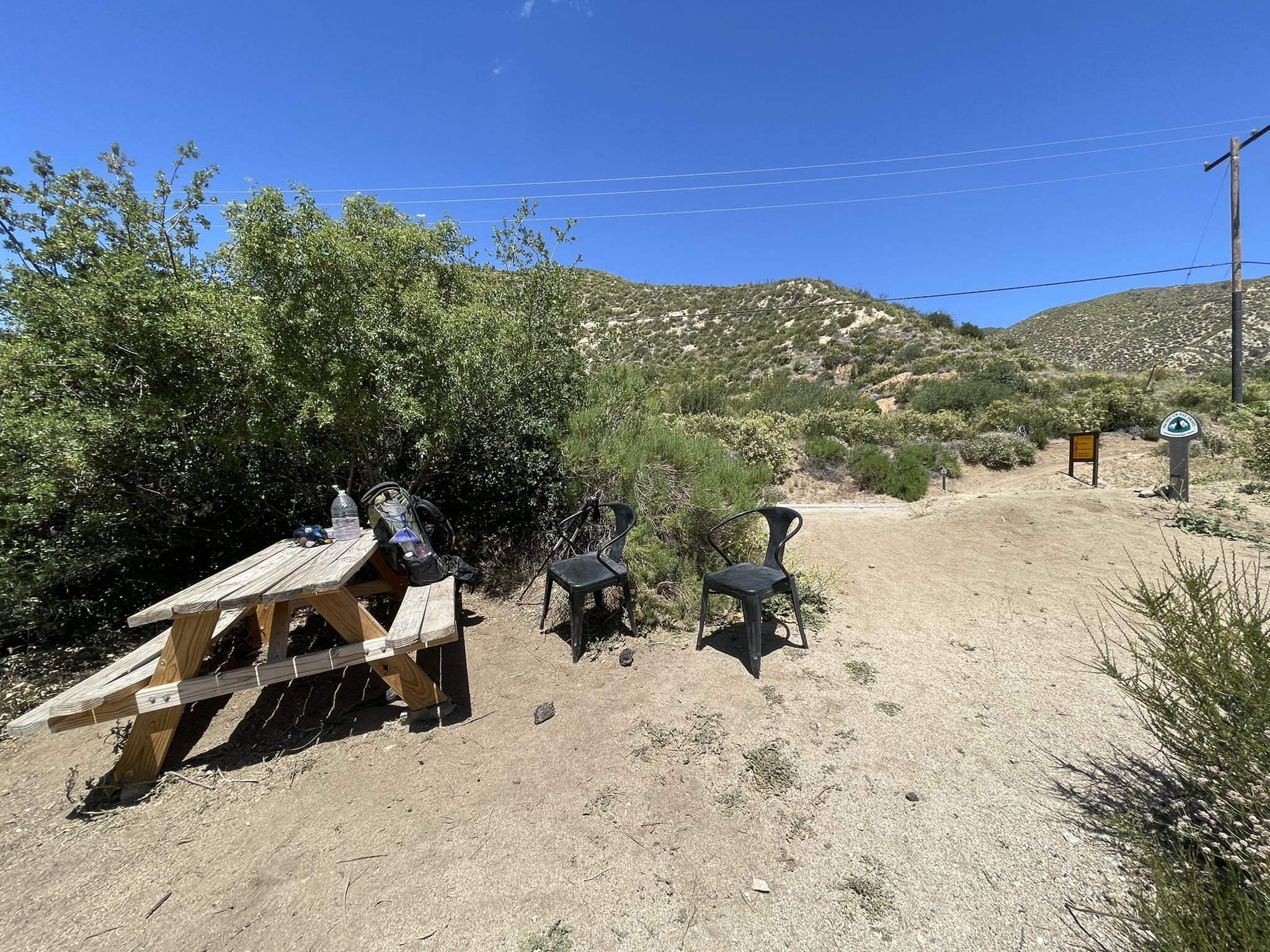 Picnic table and chairs in a dry, scrubby landscape under a bright blue sky. - San Francisquito Canyon Road – Lake Elizabeth loop from Leona Valley