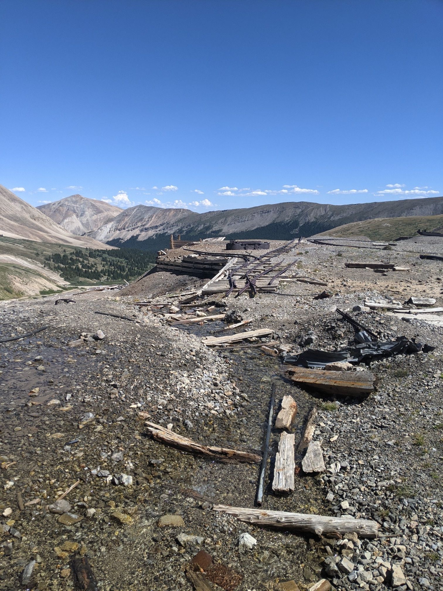 Rocky, barren mountain landscape with scattered wooden debris under a clear blue sky. - Dauntless Mine