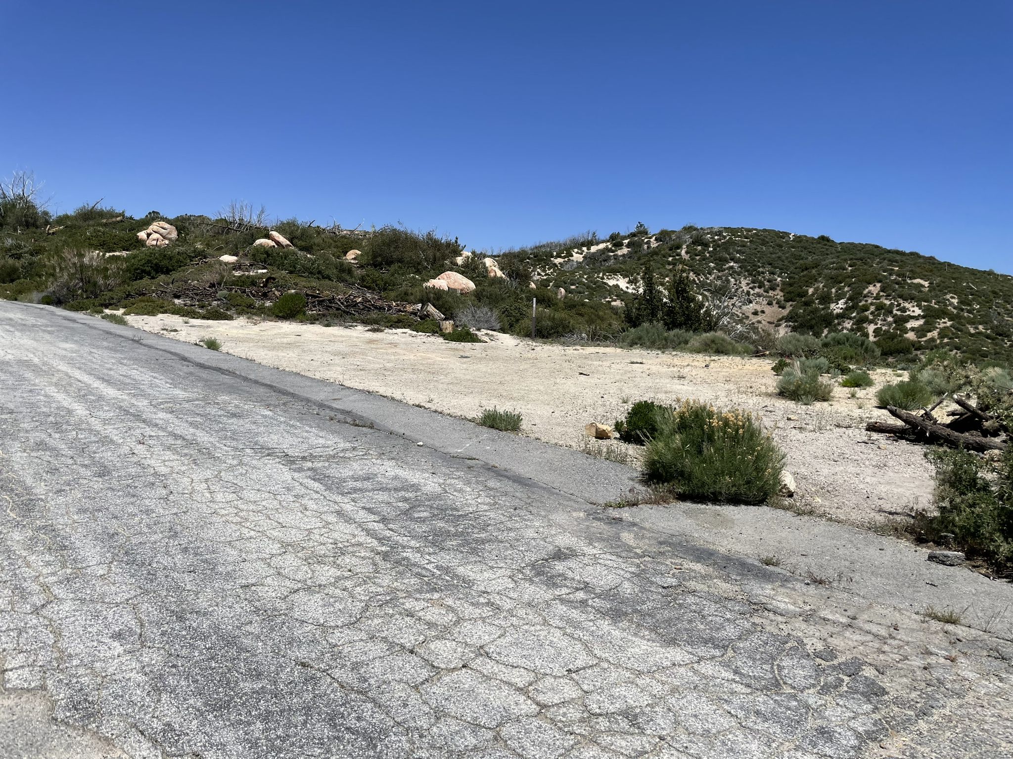 Cracked road leading to a dry, open area with sparse vegetation and hills. - Mount Gleason Loop