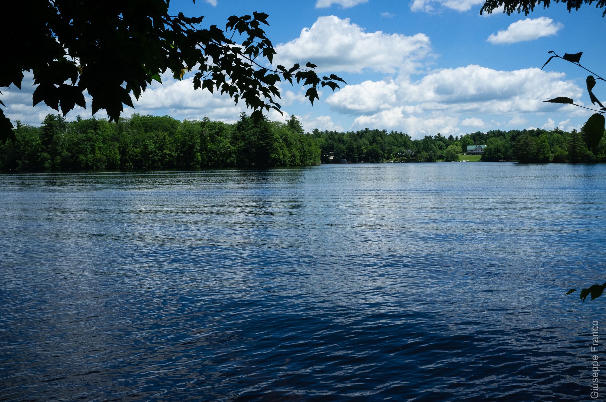 Bright daylight over a calm lake with a forested shoreline and cloudy sky. - Tolland State Forest loop