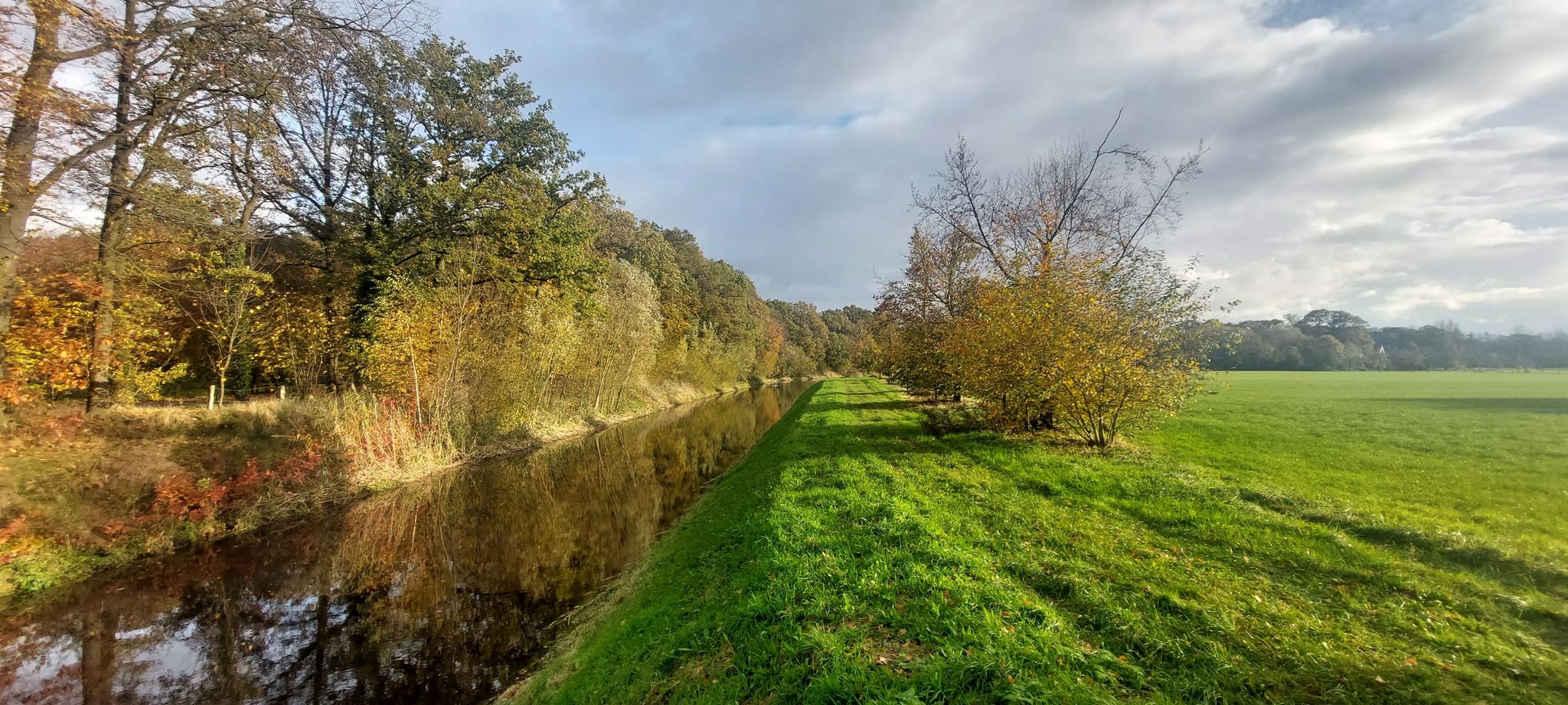 Blik over de Bornsche Beek vanaf de asfaltweg, in de goudgloed van de najaarszon