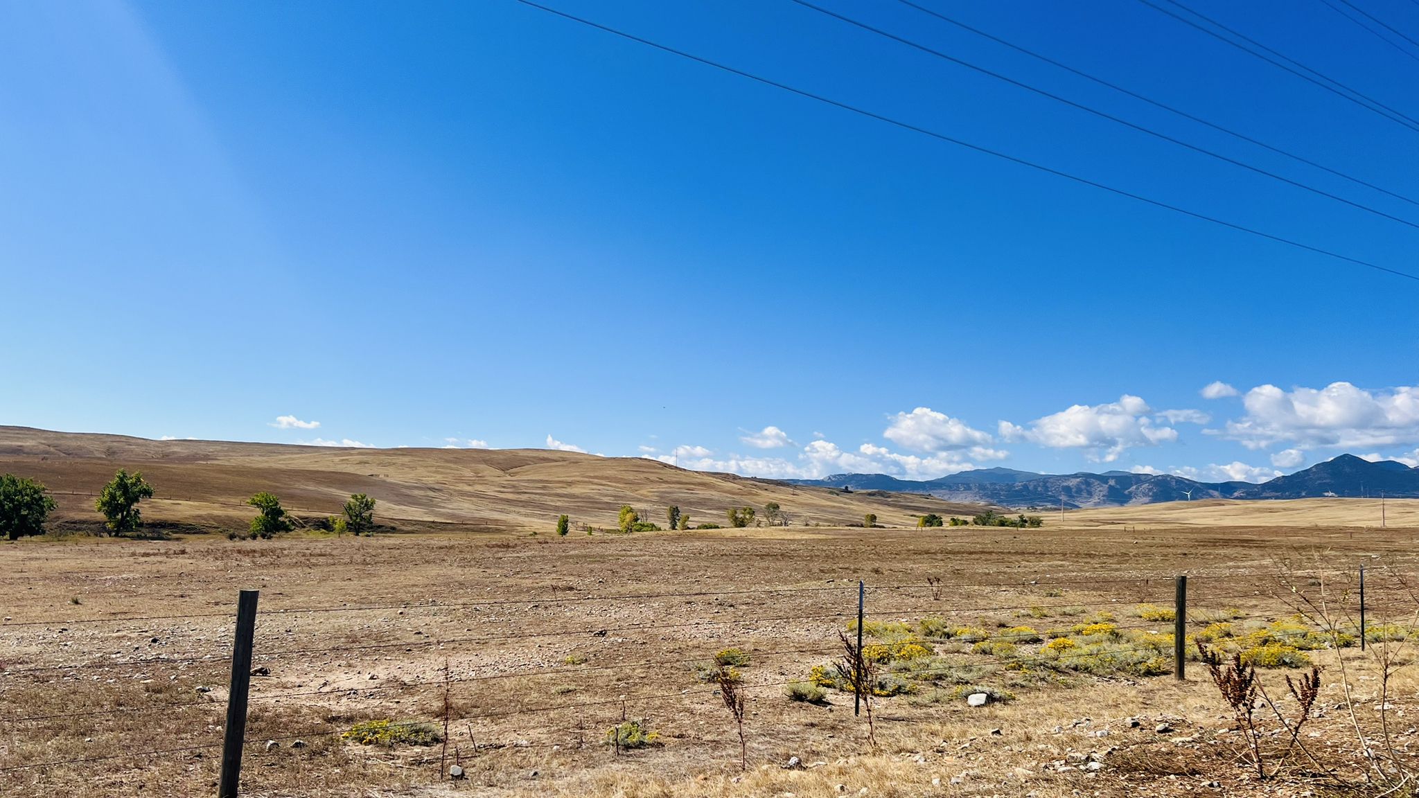 Expansive dry fields and rolling hills under a bright blue sky with power lines. - Meadowlark Trail – Marshall Mesa view loop from Superior