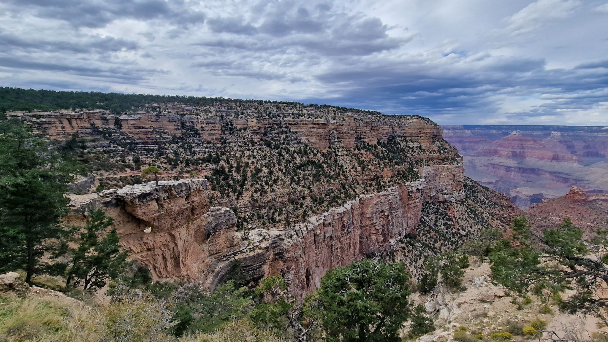 Expansive canyon landscape with layered rock formations under a cloudy sky. - 1.5 Mile Resthouse via Bright Angel Trail – Grand Canyon National Park