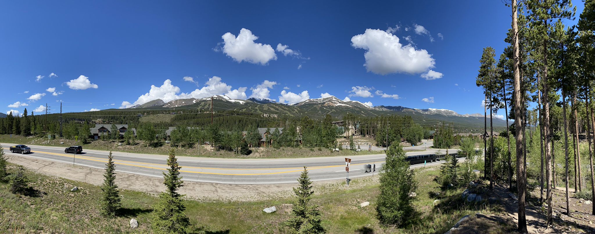 A wide highway with cars, flanked by trees and distant snow-capped mountains. - Illinois Creek Trail loop from Breckenridge