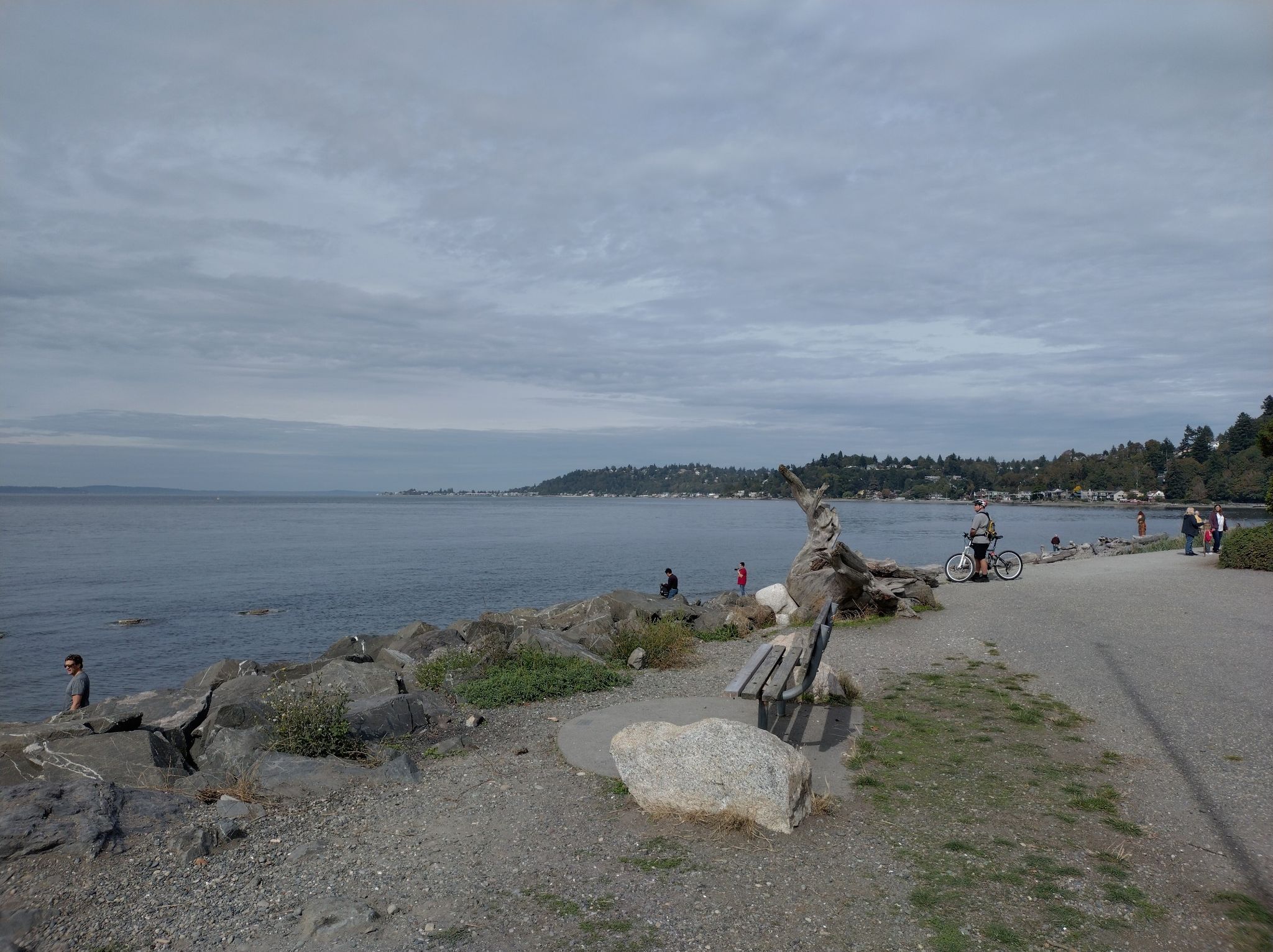 Overcast day at a rocky waterfront with people walking and cycling. - Lincoln Park Trail loop