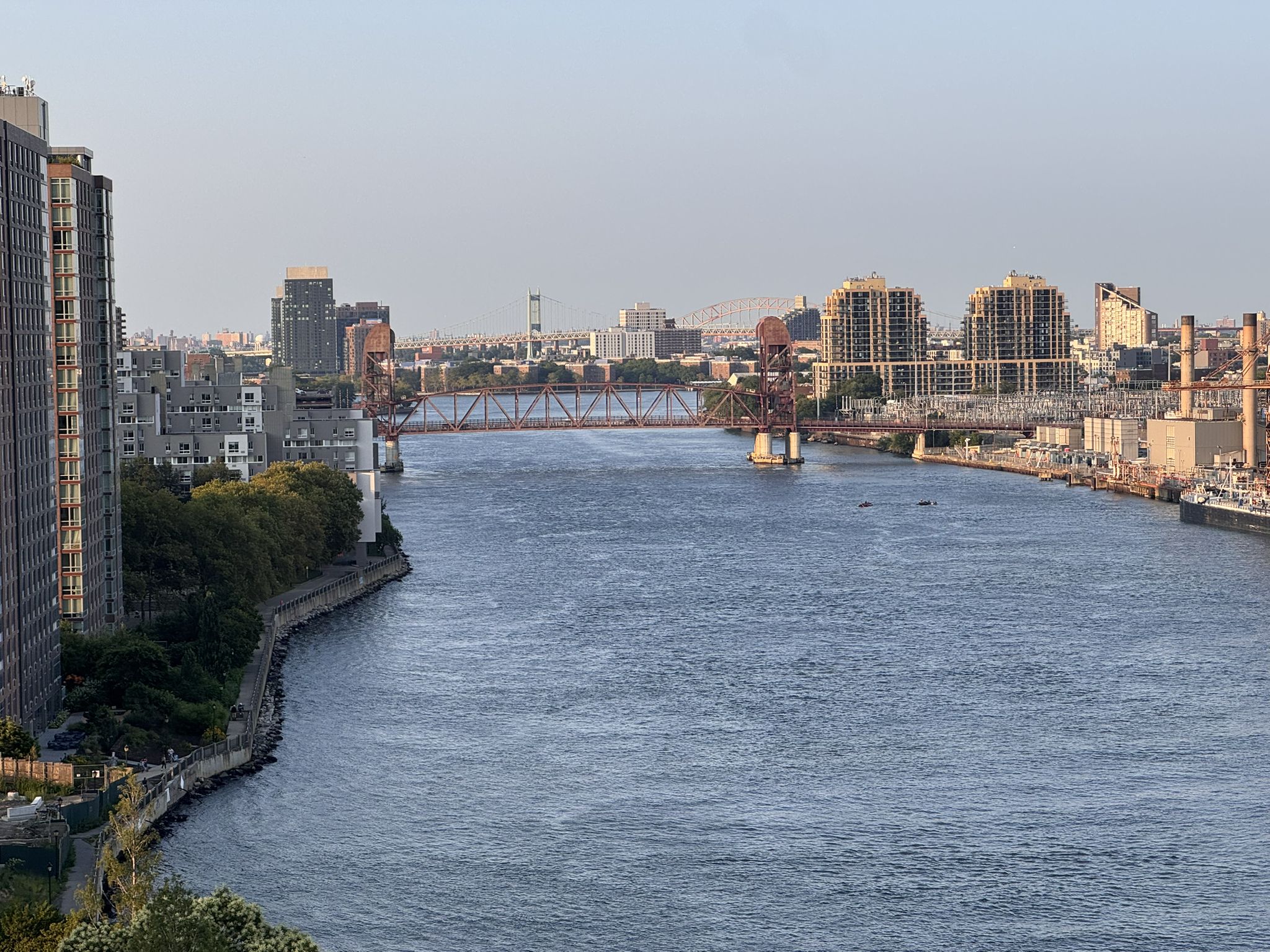 Wide river flowing through an urban landscape with a large bridge. - Roosevelt Island Tramway – Queensboro Bridge Bike Path loop from 39th Avenue