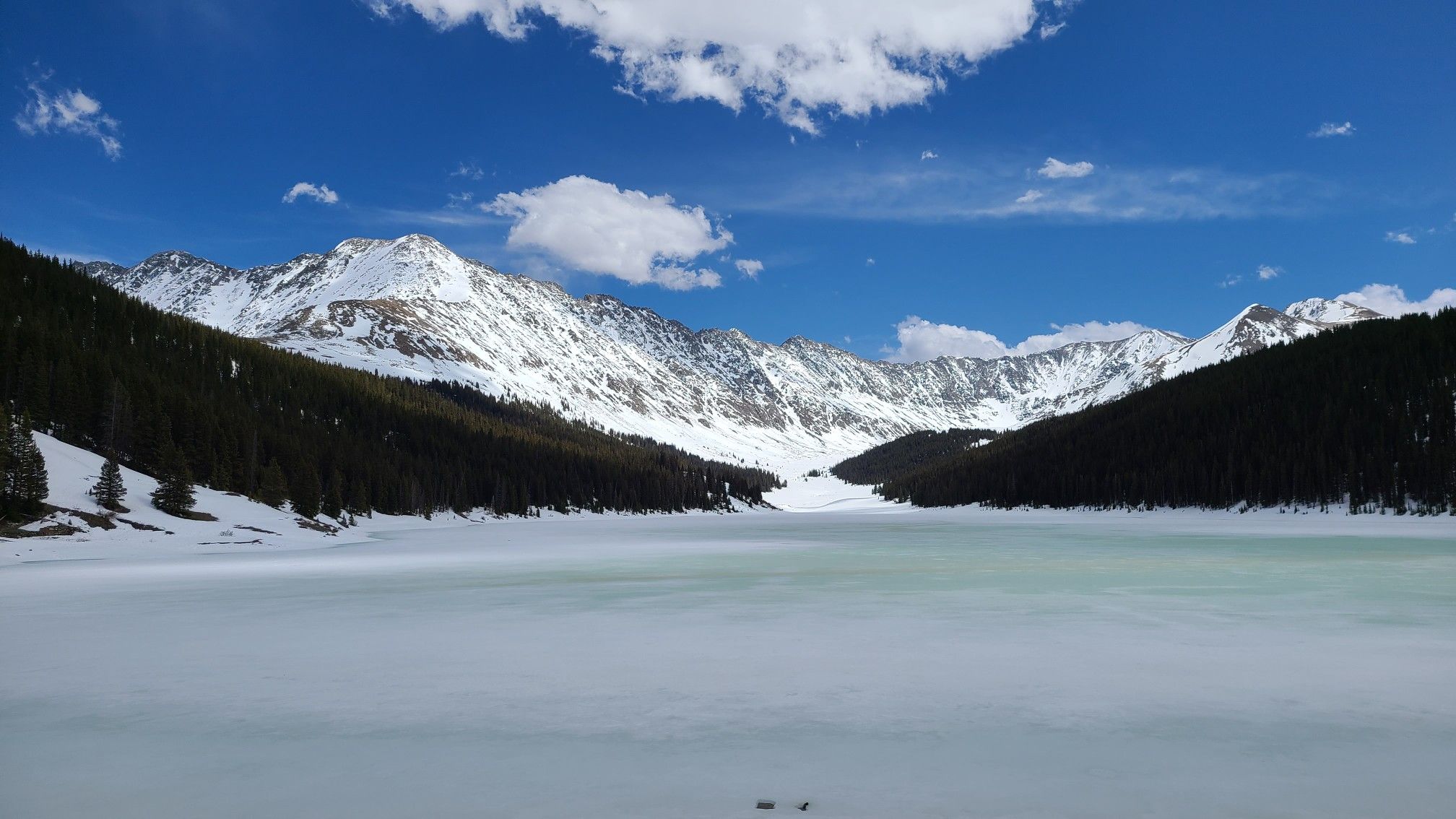 Bright alpine scene with a frozen lake, snow-capped mountains, and blue sky. - Fremont Pass Recreational Pathway