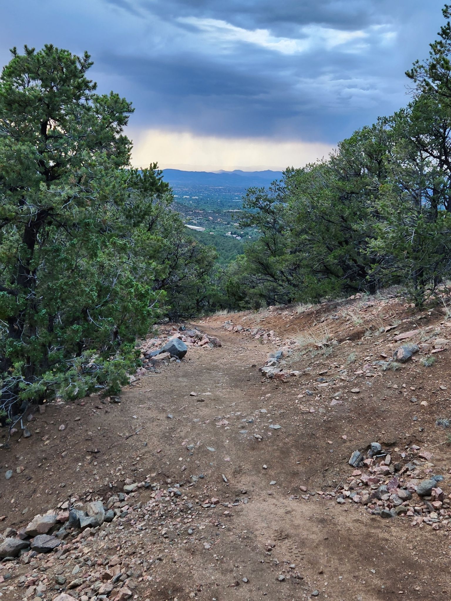 Dirt path descending through trees towards a distant valley under cloudy sky. - Atalaya Mountain via Atalaya Trail and Dale Ball Trails Loop
