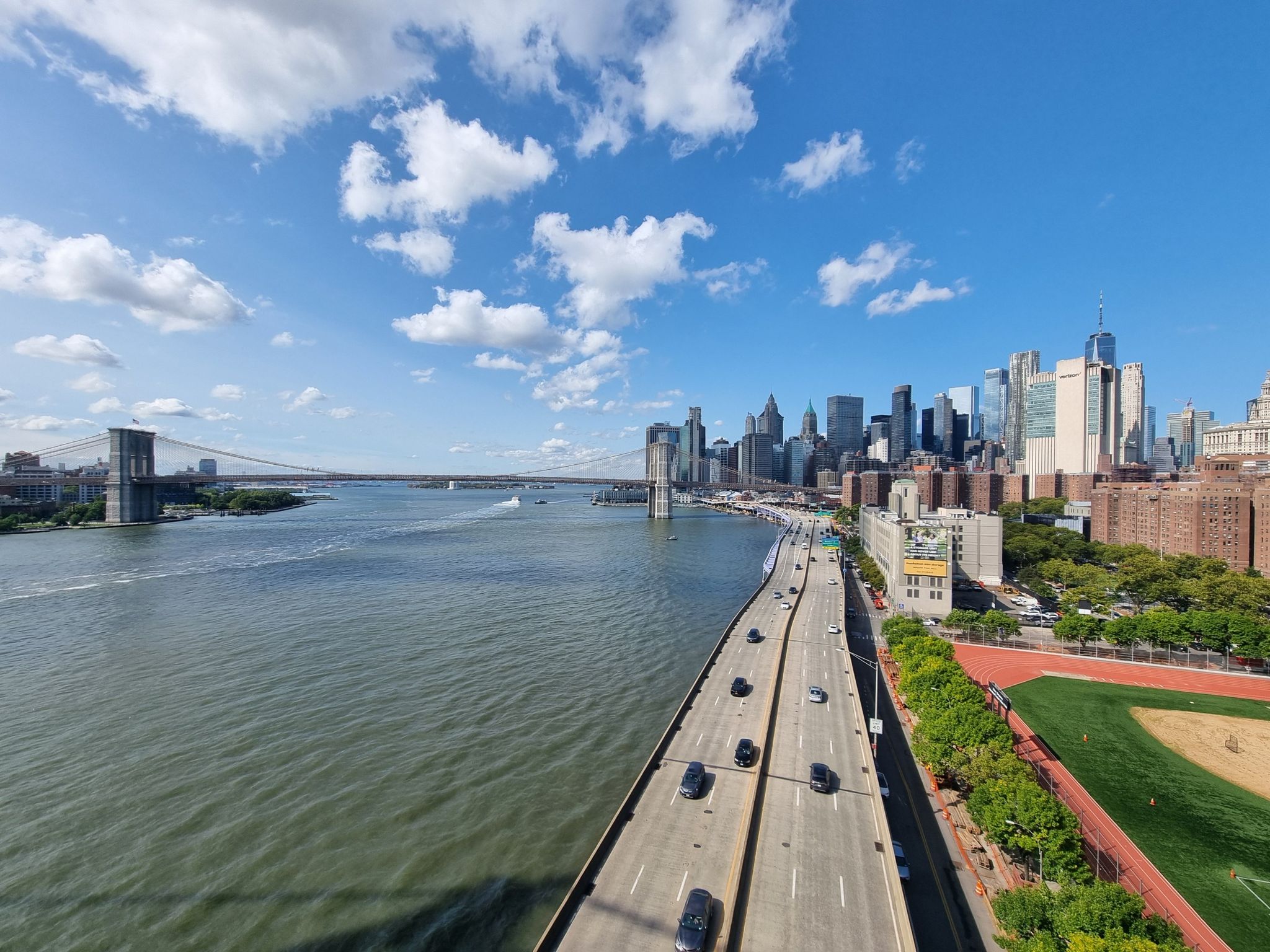 Elevated view of a busy highway next to a river and distant city skyline. - Manhattan Waterfront Greenway and Central Park Loop