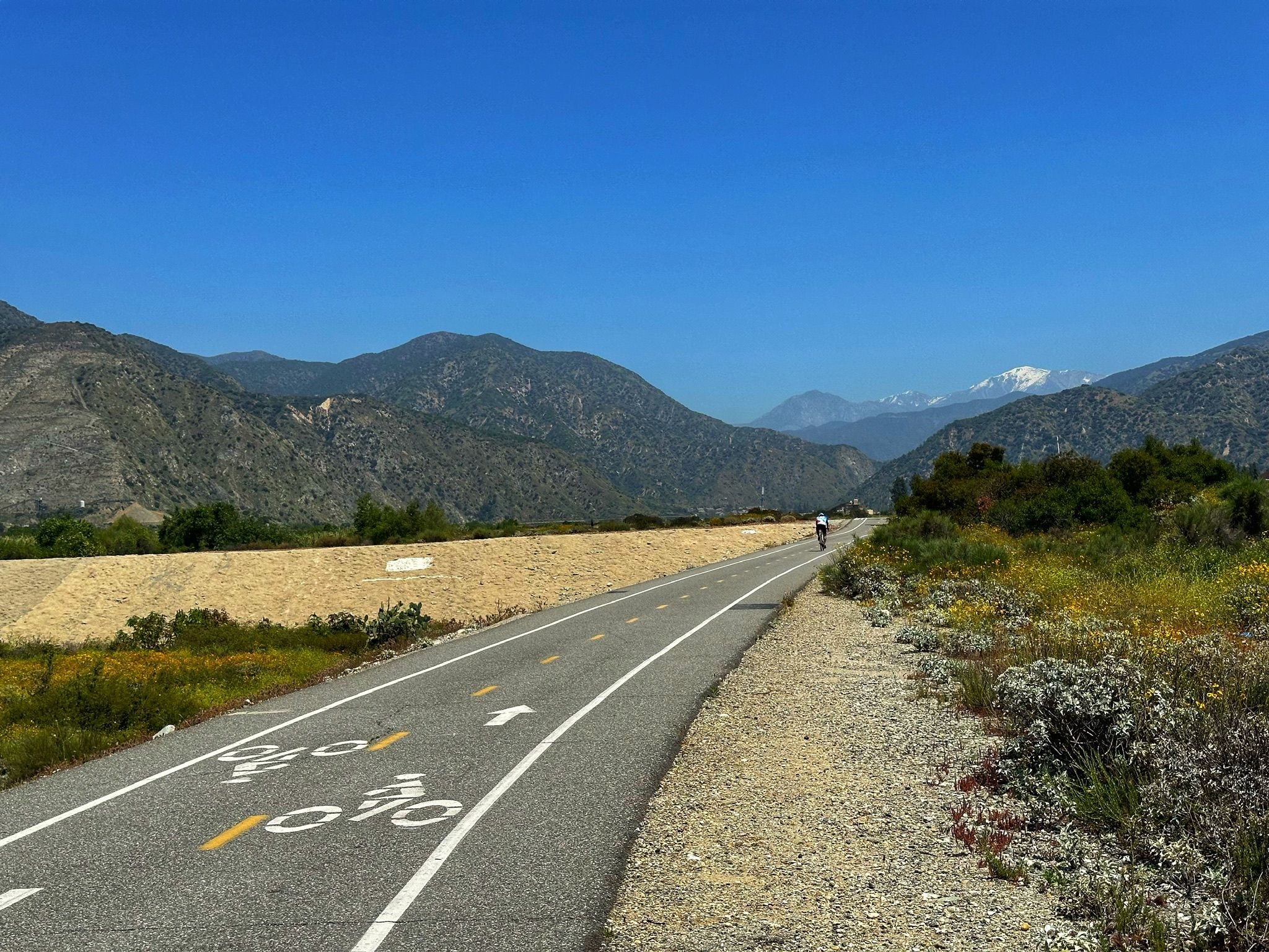 Paved path with bike lane markings, a cyclist, and distant mountains. - View of San Gabriel Mountains loop from Azusa
