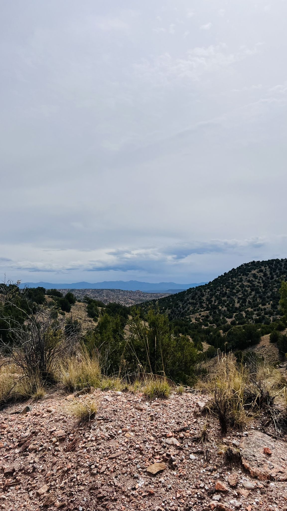 Rocky foreground overlooking a distant valley and hills under cloudy skies. - Joseph’s Mine Trail