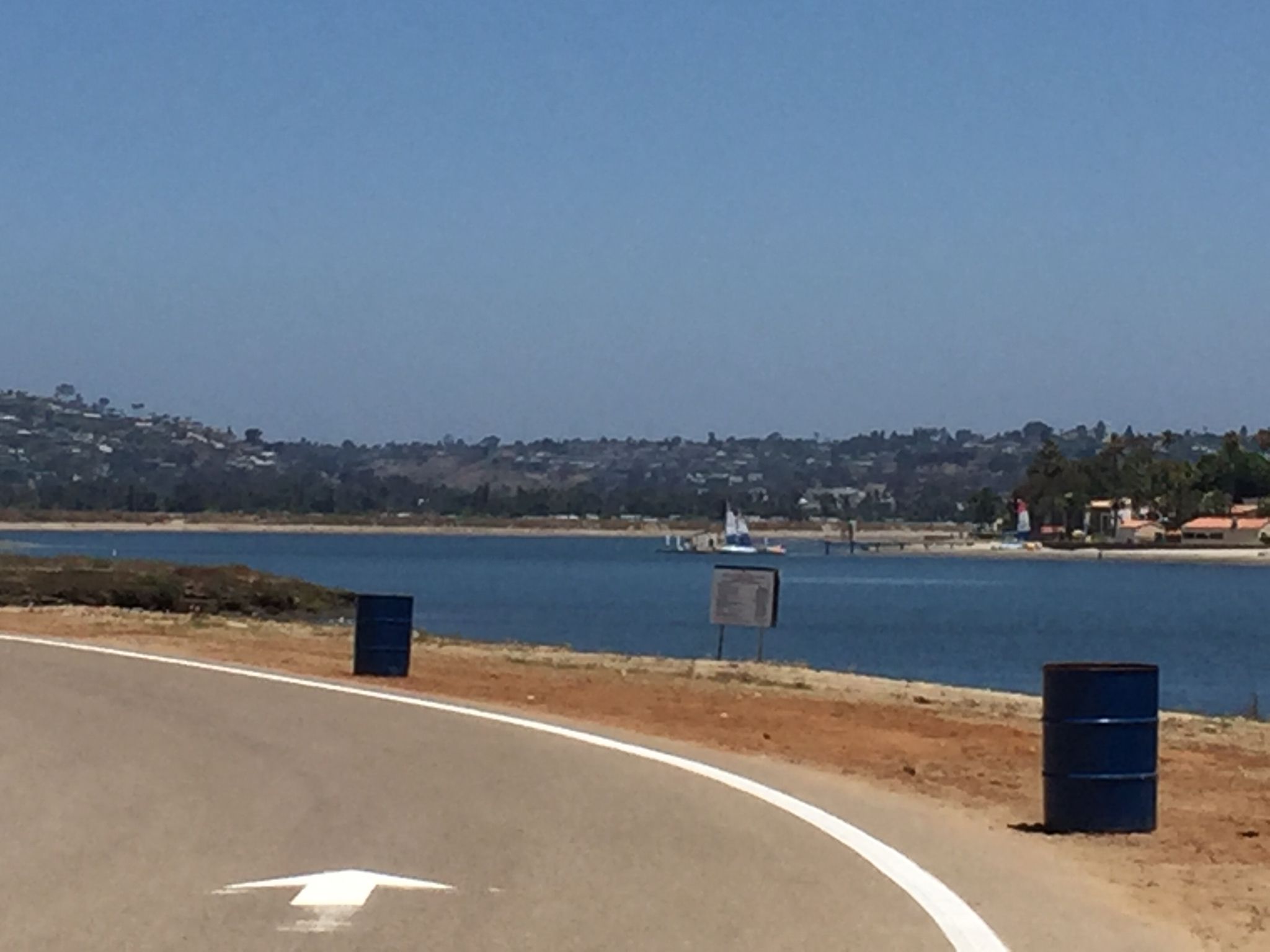 Sunny day with a paved road curving beside calm blue water. - Fiesta Island run loop