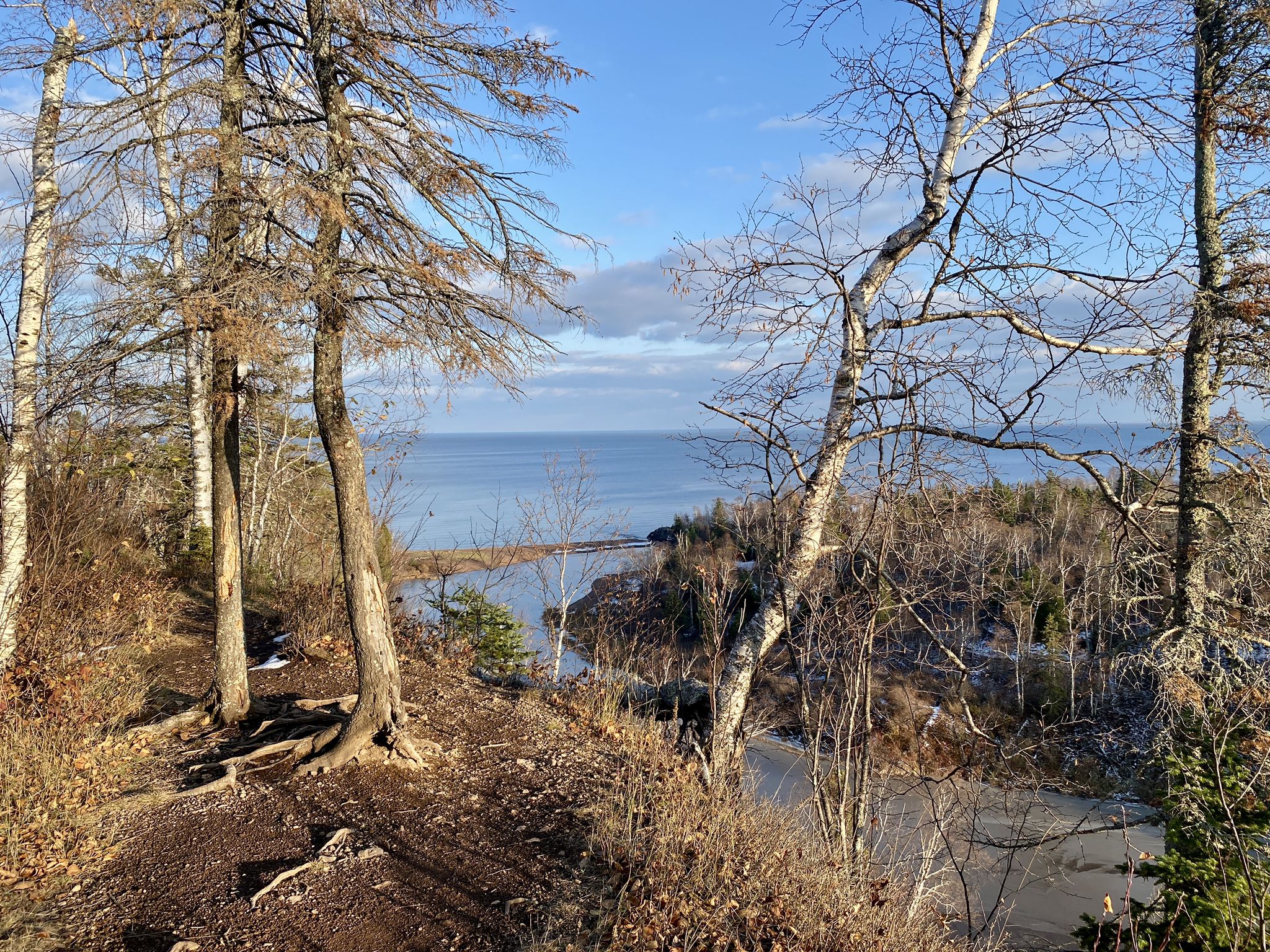 Forest path overlooking a large lake under a bright sky. - Agate Beach via Gitchi-Gami Trail