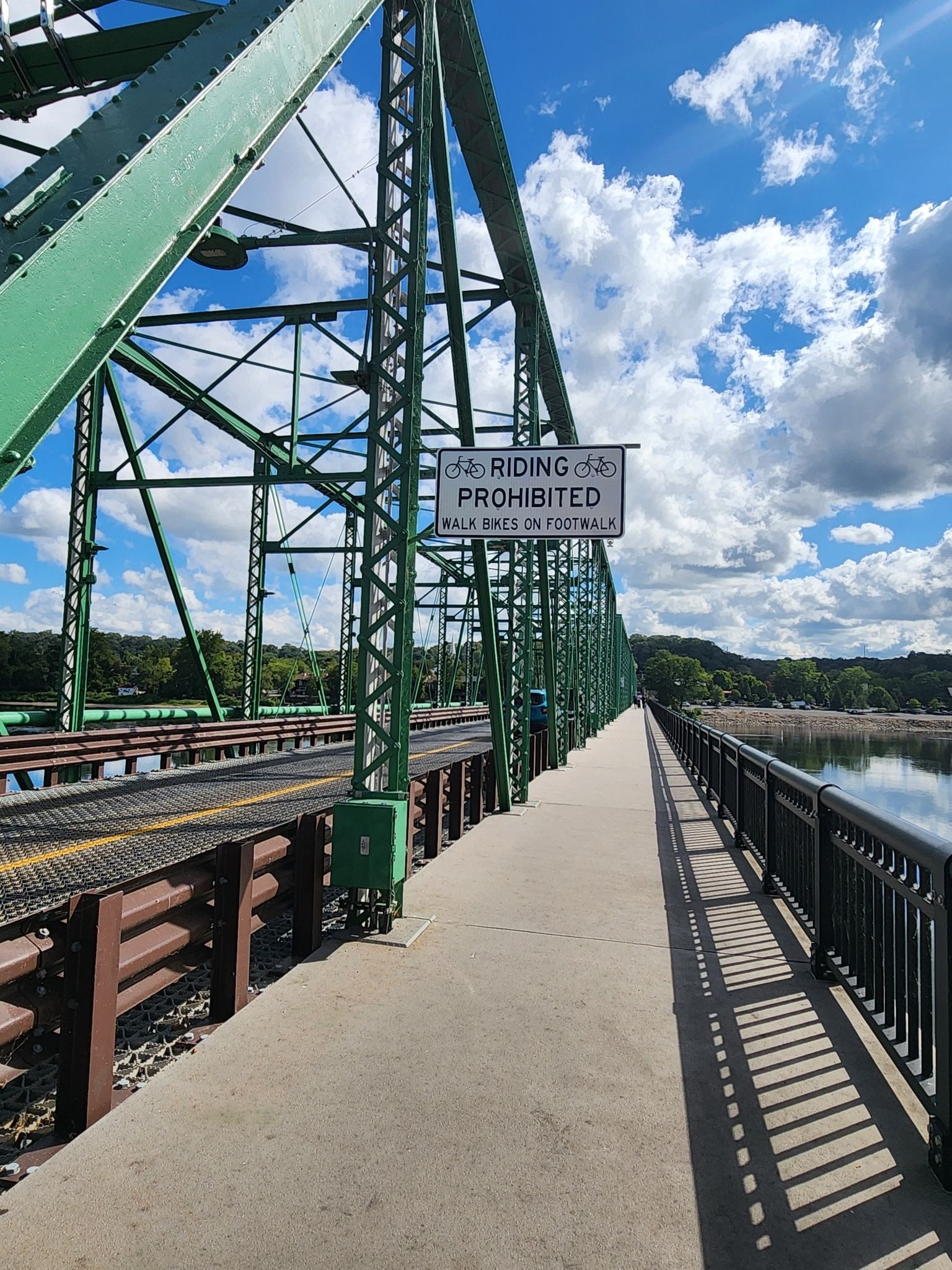 Pedestrian path on a green metal truss bridge with a "no riding" sign. - New Hope – View of the Delaware River loop from New Hope Station