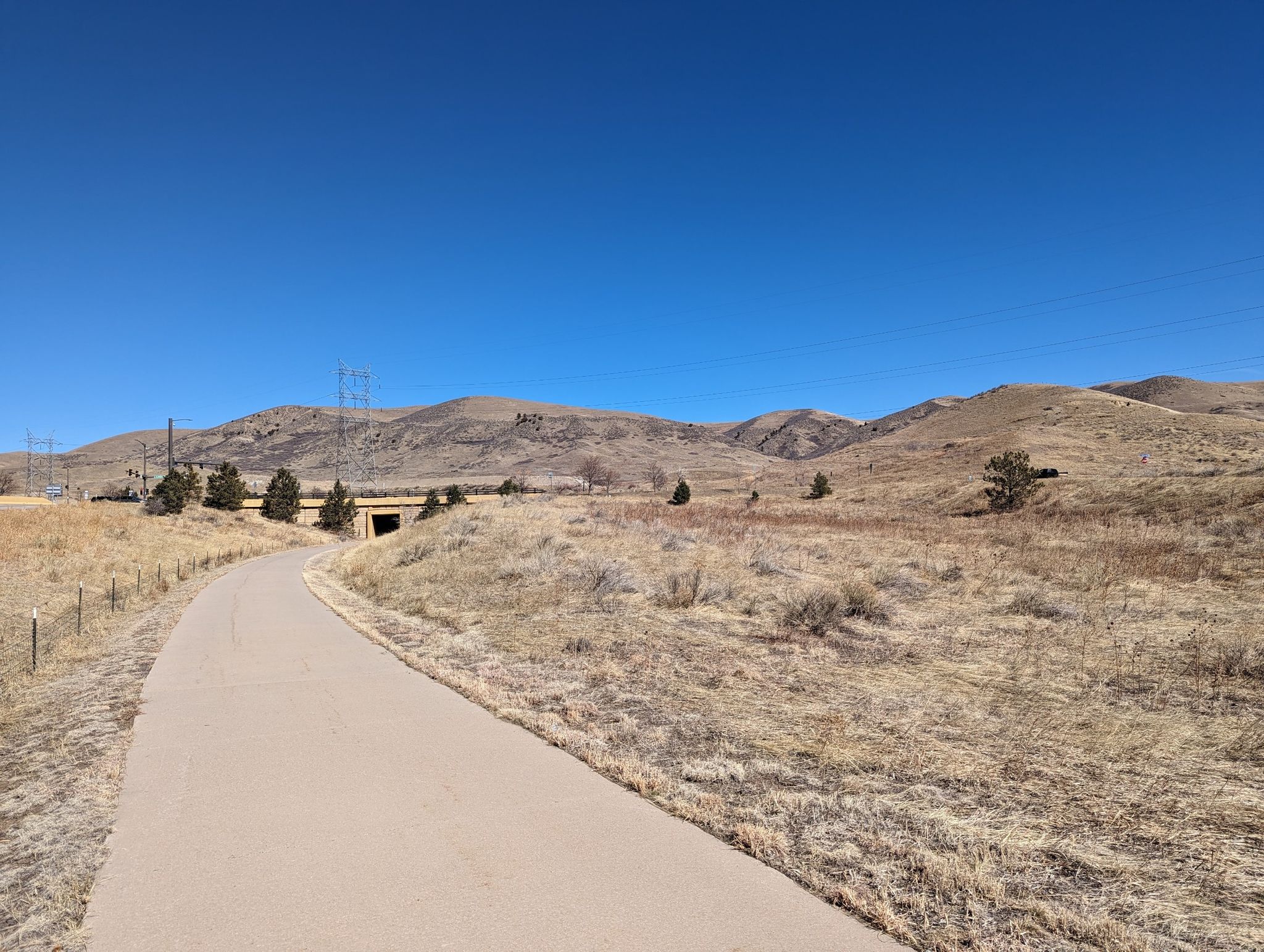 Paved path through dry hills, clear blue sky, and distant tunnel. - Bike loop from Red Rocks College