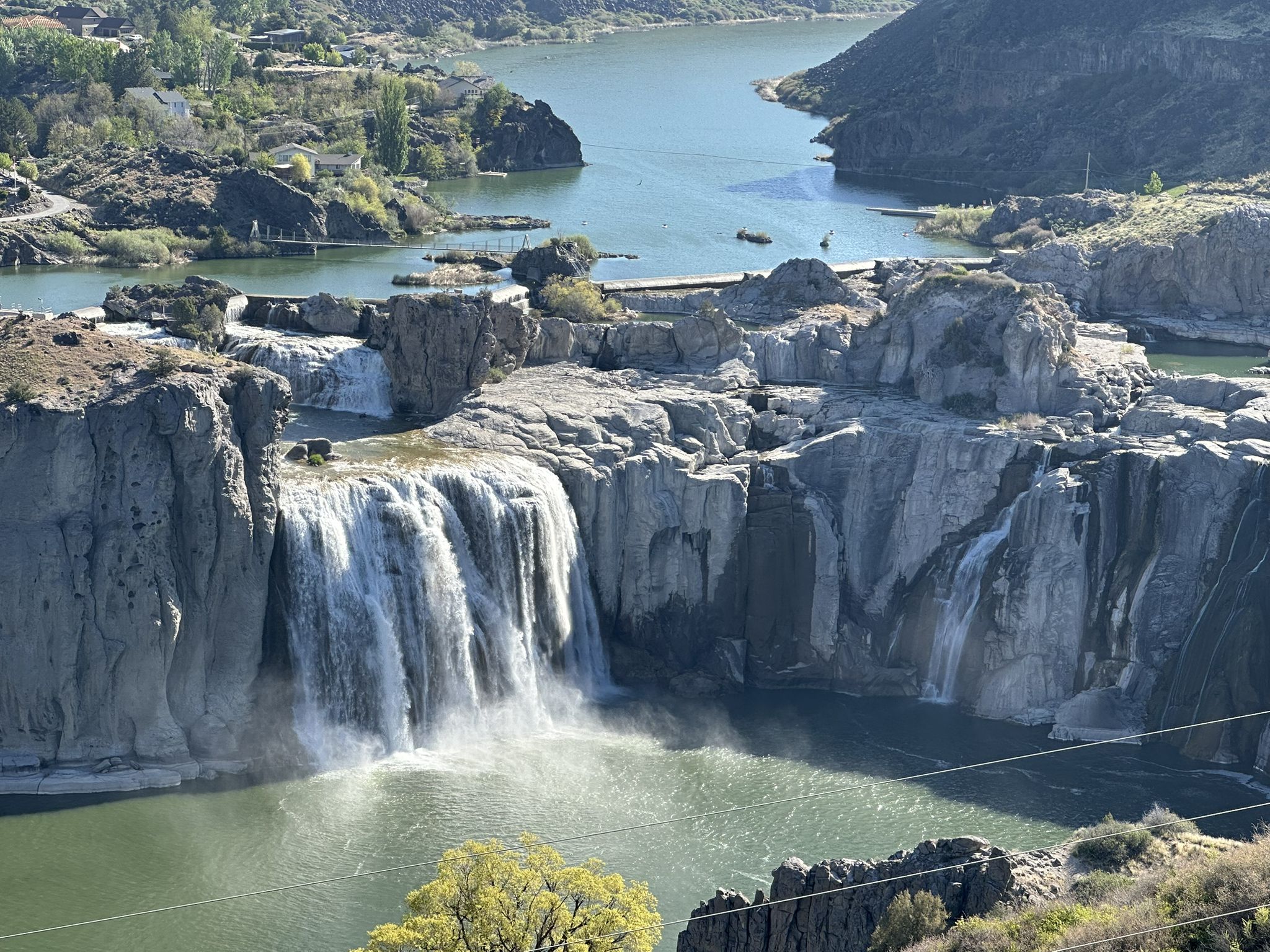 Multiple waterfalls cascade into a wide river under a bright sky. - Shaded Stone Seating Area loop from Twin Falls Idaho Temple
