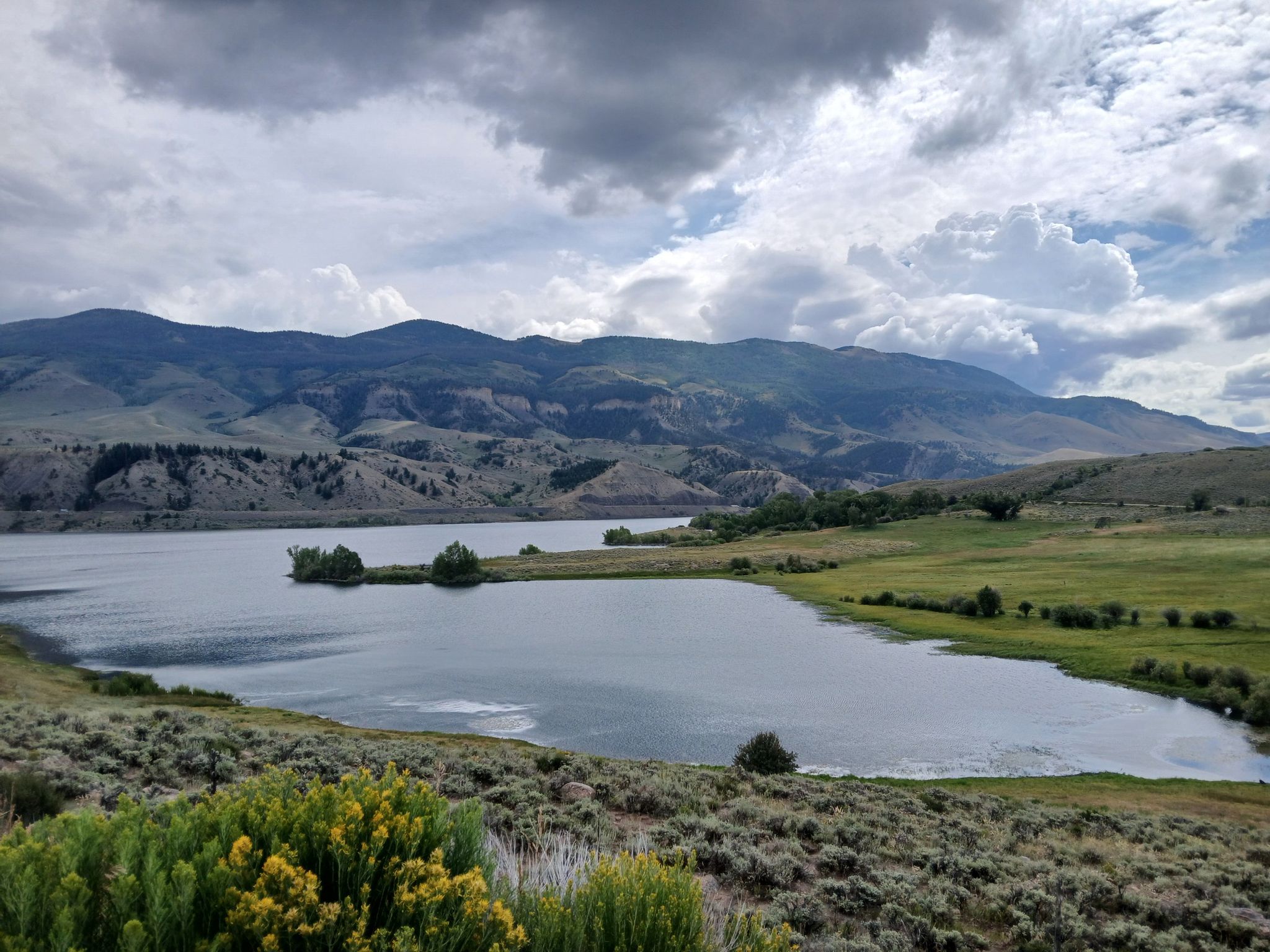 A lake surrounded by green hills and mountains under a cloudy sky. - Green Mountain Reservoir Loop