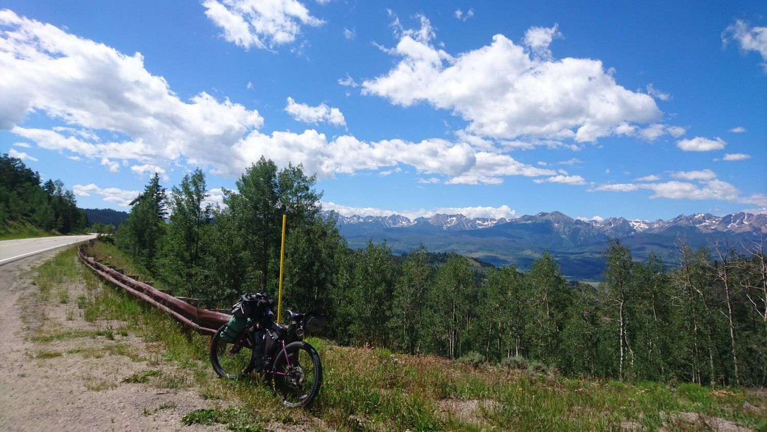 A bicycle parked beside a road overlooking distant snow-capped mountains. - Ute Peak Trail