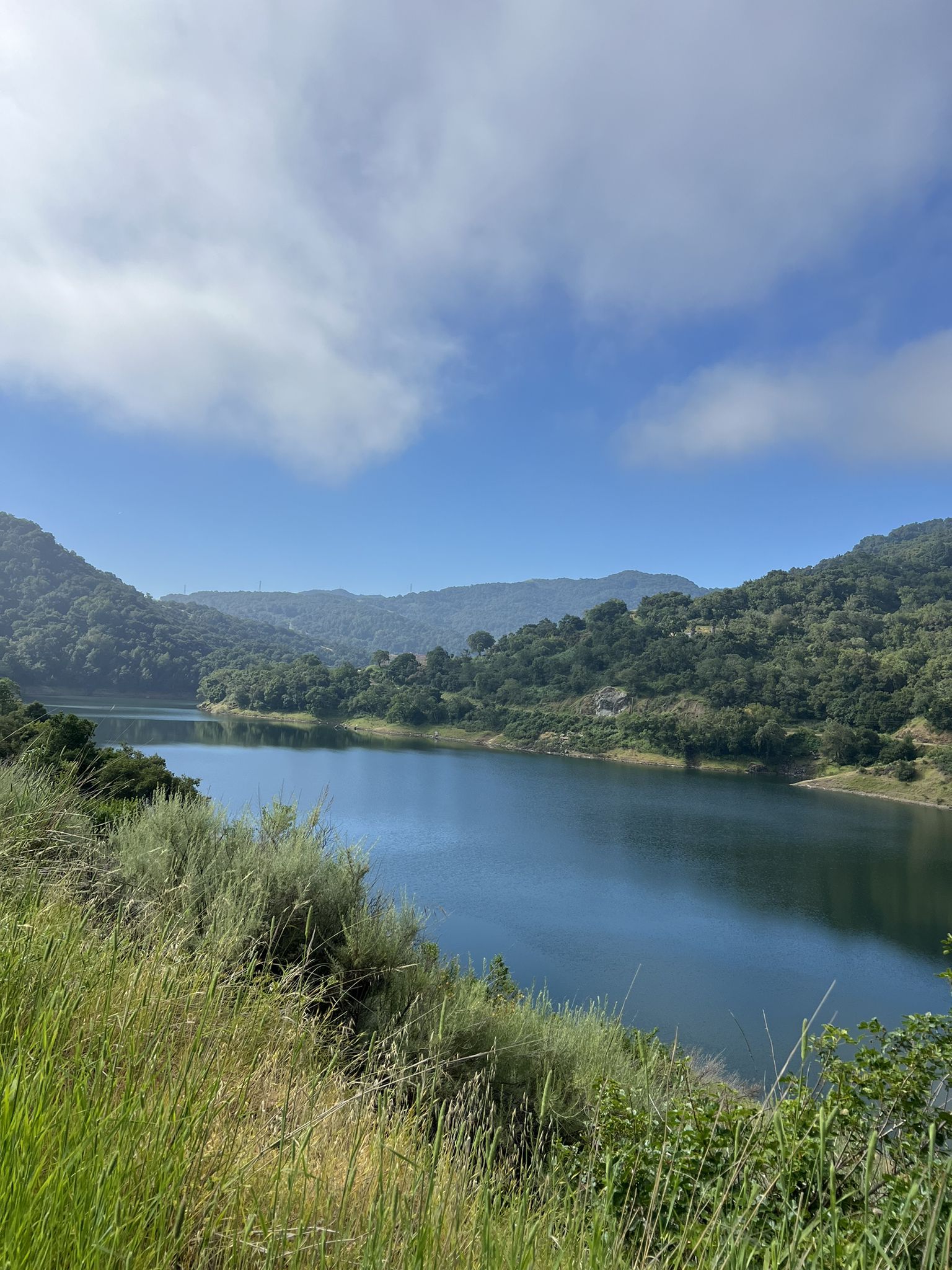 A serene blue lake nestled among green hills under a partly cloudy sky. - Guadalupe and Mine Hill Trail Loop