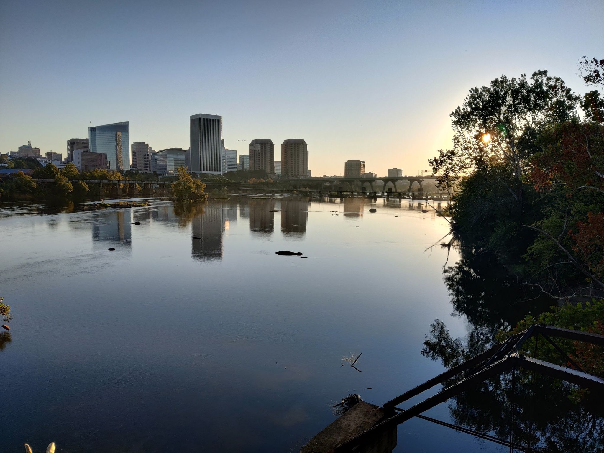City skyline reflected in a calm river at sunset, with a distant bridge. - Flooded Quarry Pond – Belle Island loop from Richmond
