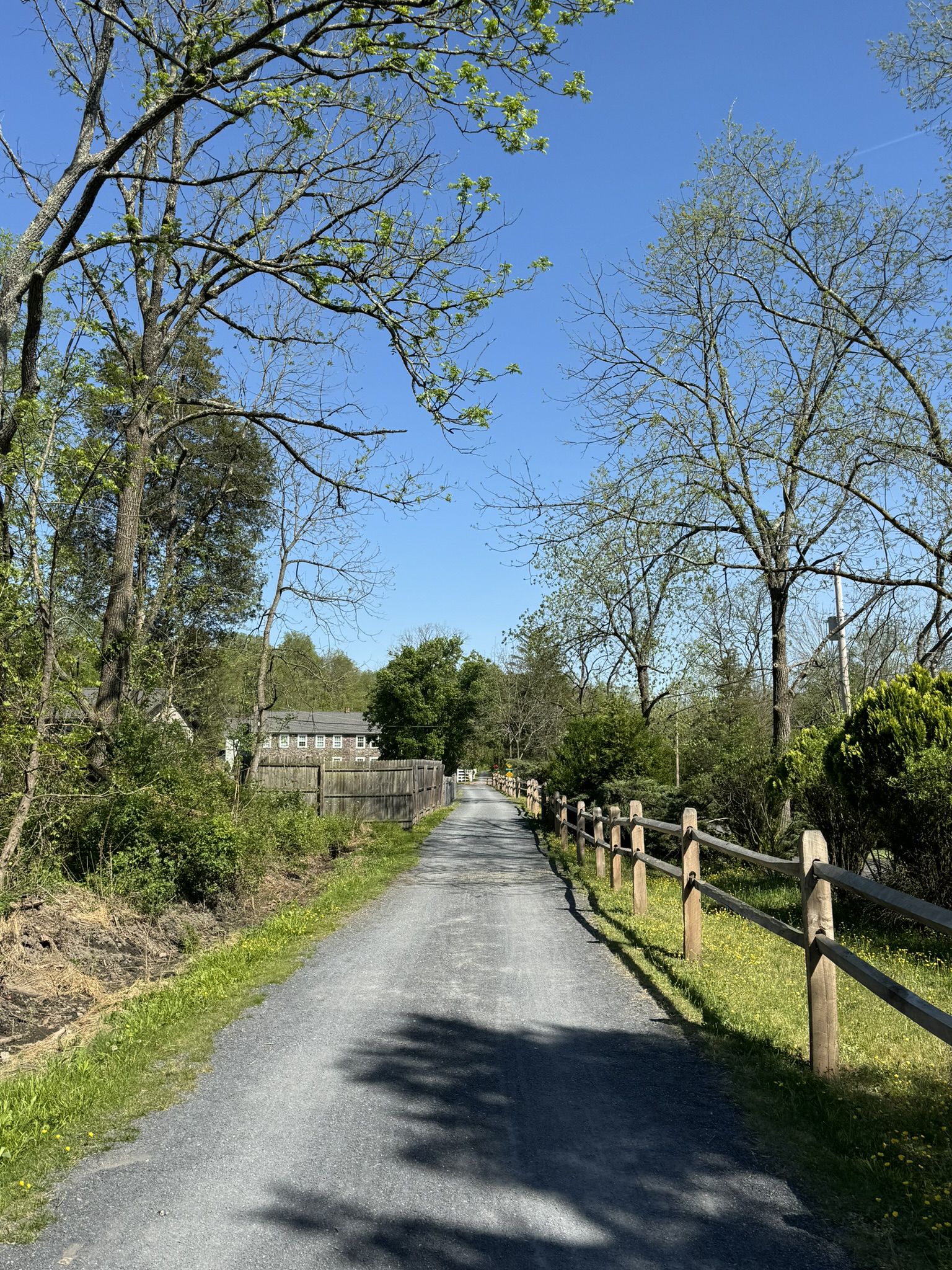 Gravel path lined with wooden fence and trees under a clear sky. - Perkiomen Trail: Perkiomenville to Spring Mount