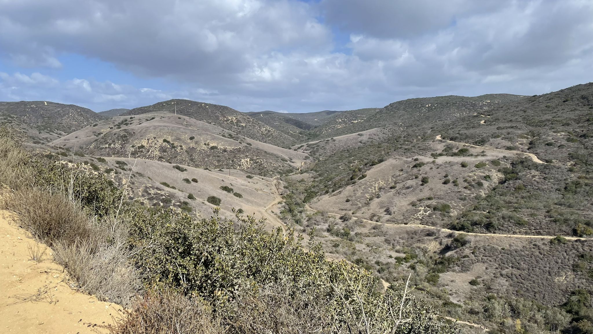 Rolling hills covered in dry and green brush under a cloudy sky. - No Name Ridge and El Moro Canyon Loop
