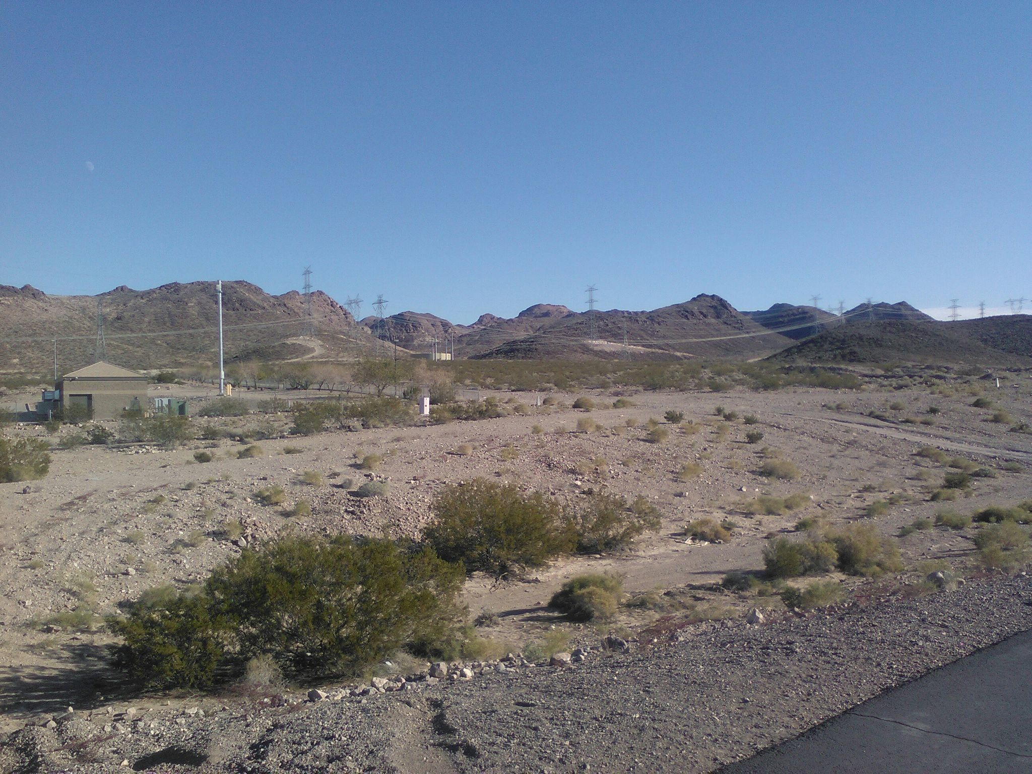 Dry desert landscape with sparse vegetation, power lines, and distant mountains. - Henderson - River Mountains Trail Loop
