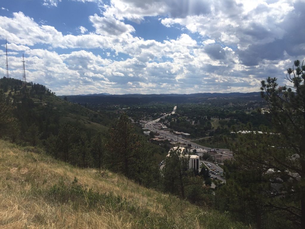 Panoramic view of a valley town and road under a partly cloudy sky. - Skyline and Dinosaur Park Loop