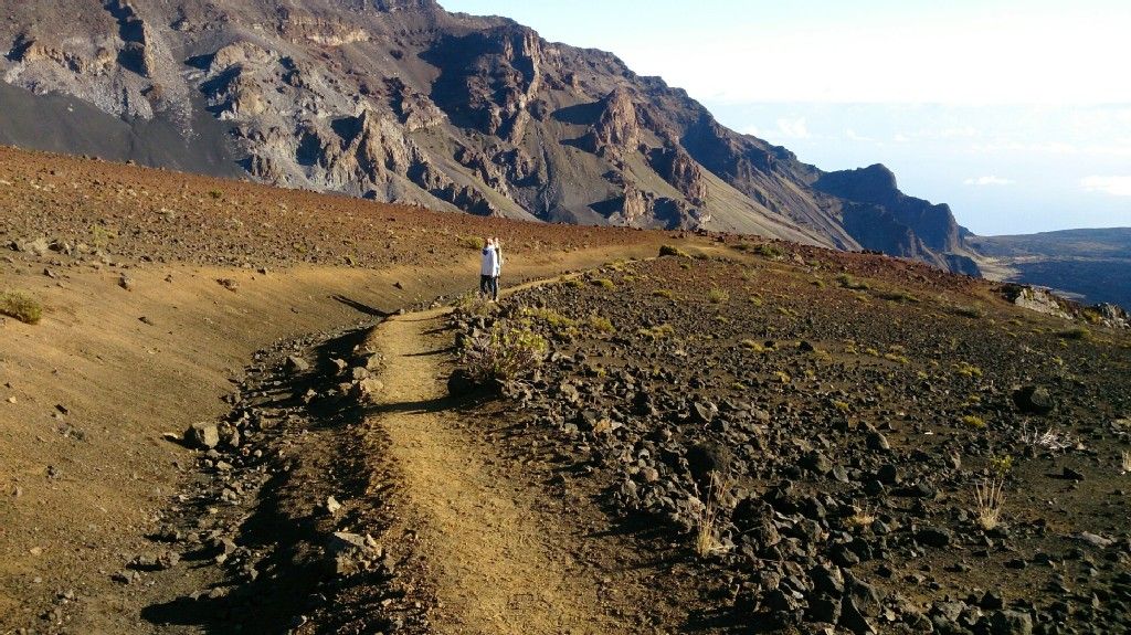 A person hiking on a dirt path through a rocky, barren landscape under bright sun. - Hiking loop from Pan-STARRS