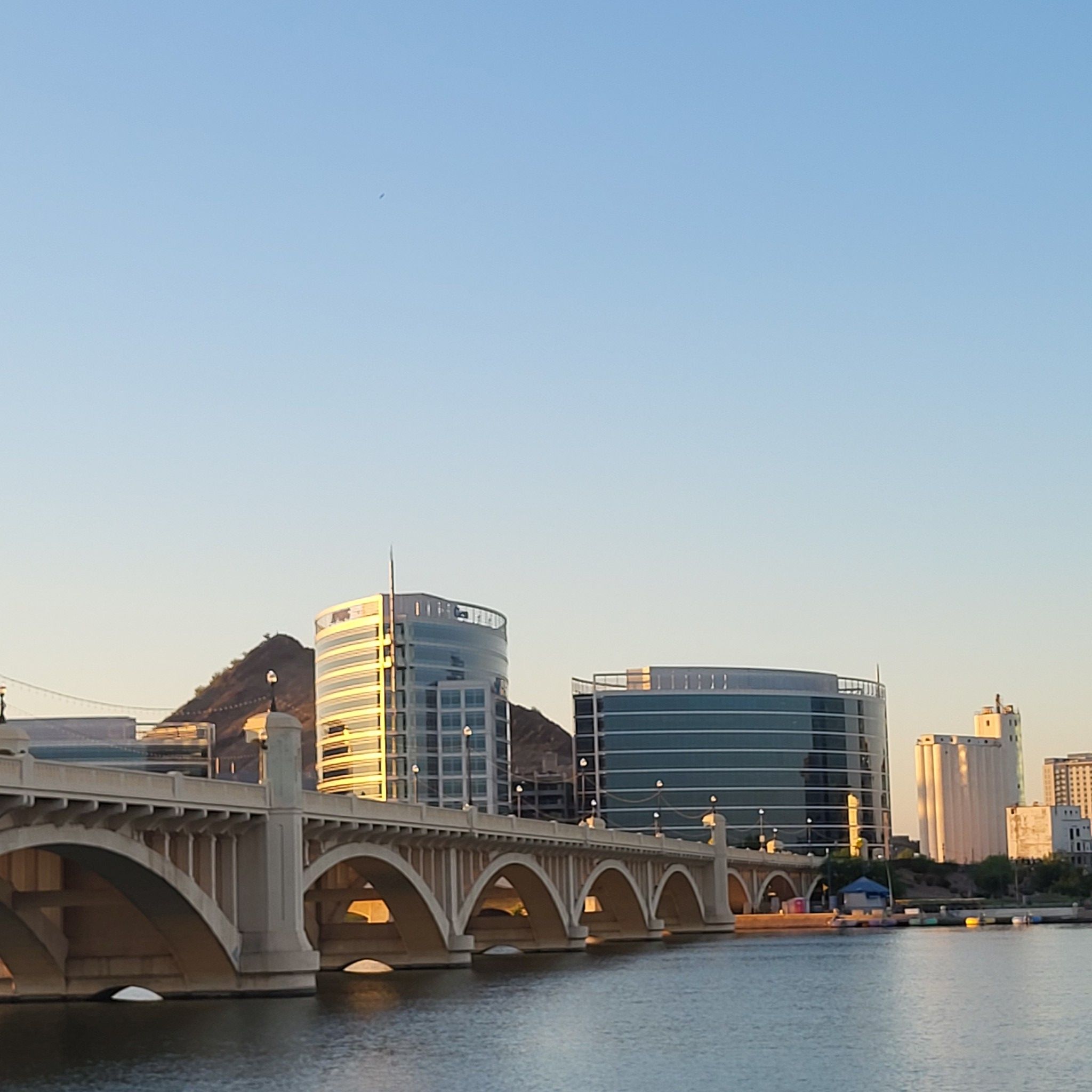 Arched bridge over water with modern buildings and a mountain at sunset. - Canal, Lizard and Loma Trail