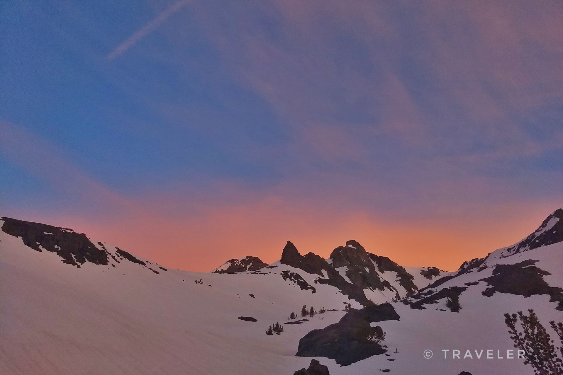 Snow-covered mountains with jagged peaks under a vibrant pink and orange sky. - Blue Canyon Trail
