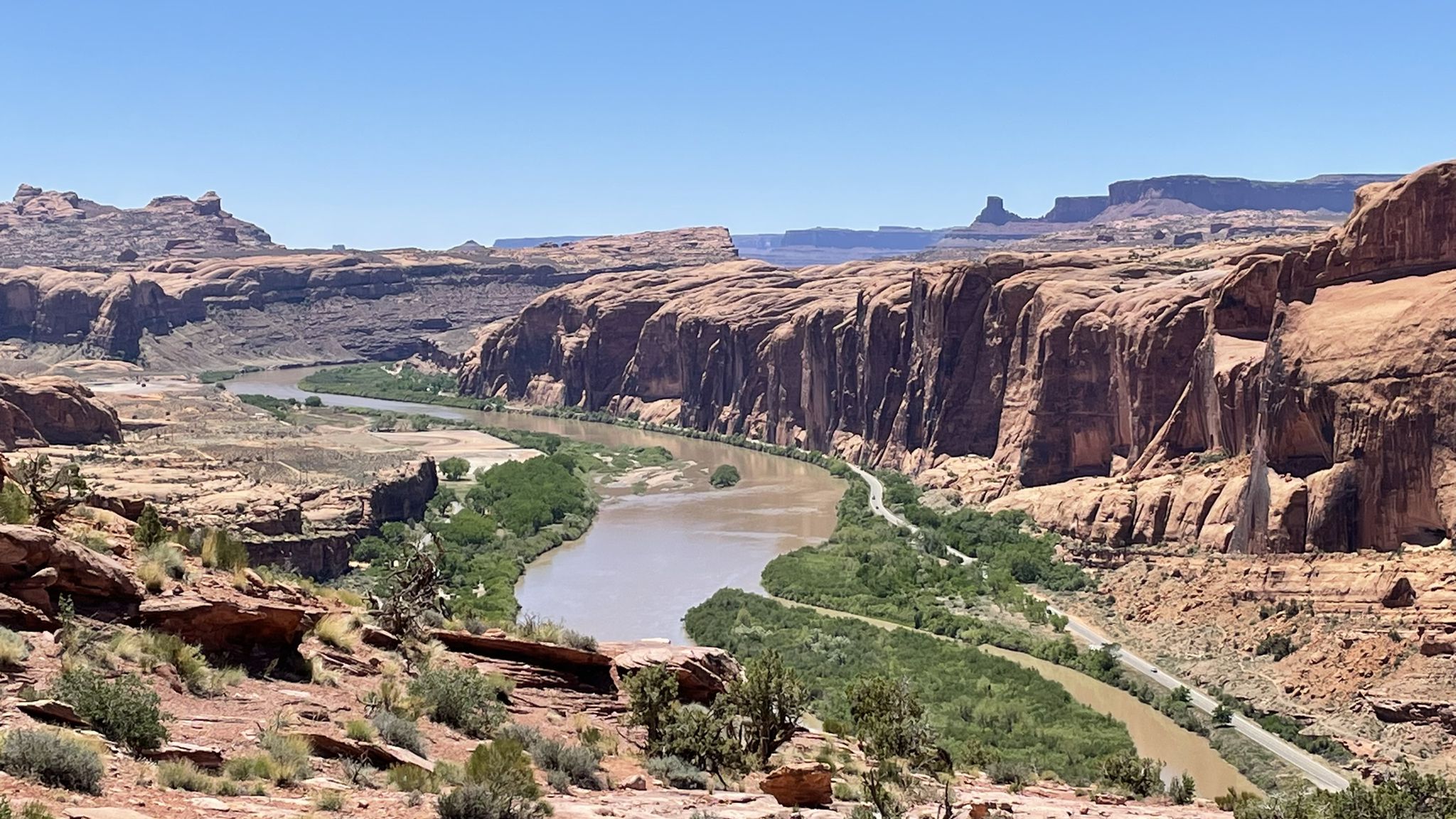 Wide view of a winding river through a desert canyon under bright sun. - The Stairmaster – Moab Rim overlook loop from Scott Matheson Wetlands Preserve