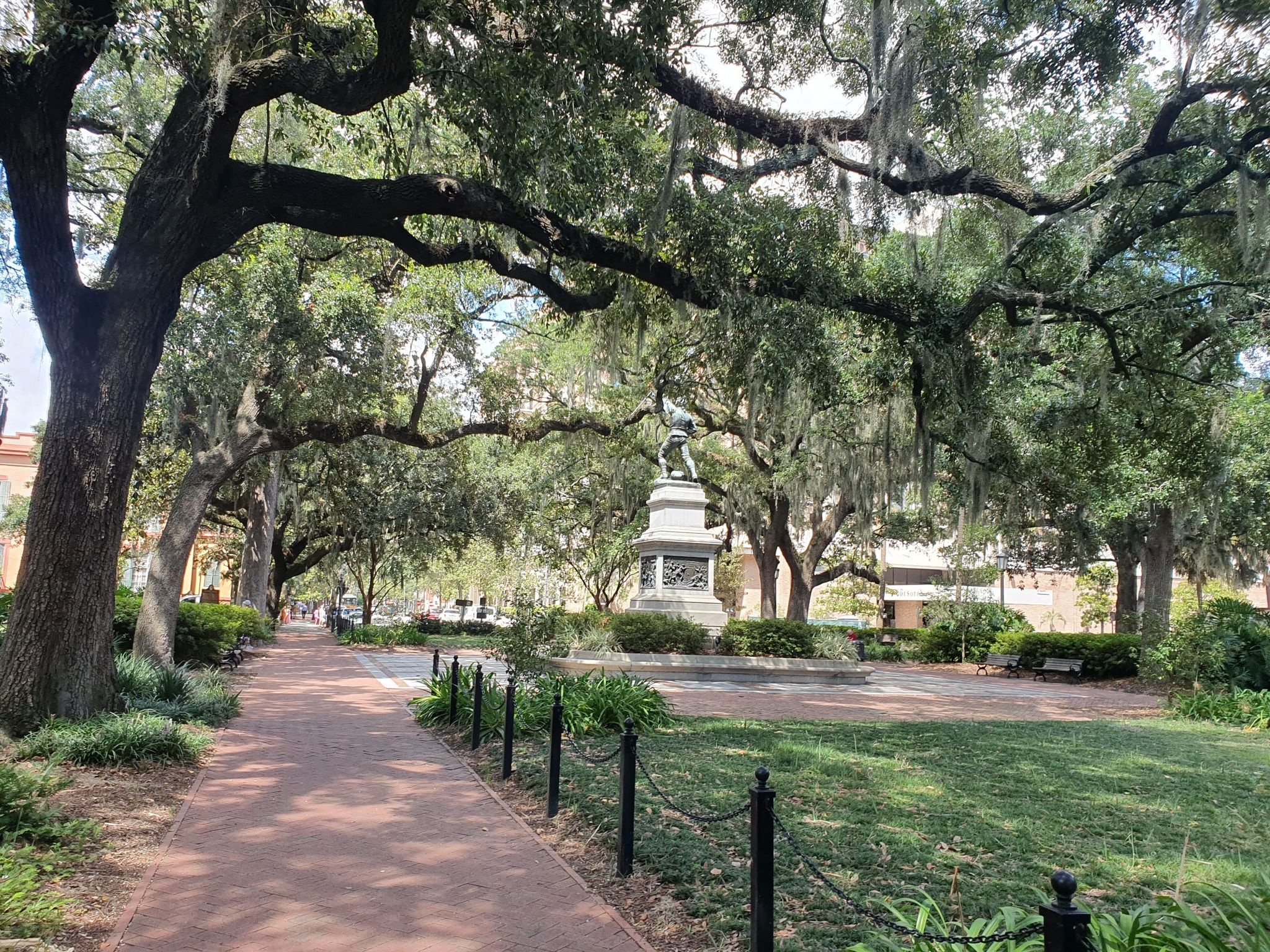 Paved park path under large moss-draped trees with a distant statue. - Monterey Square – Madison Square loop from Savannah Arts Academy