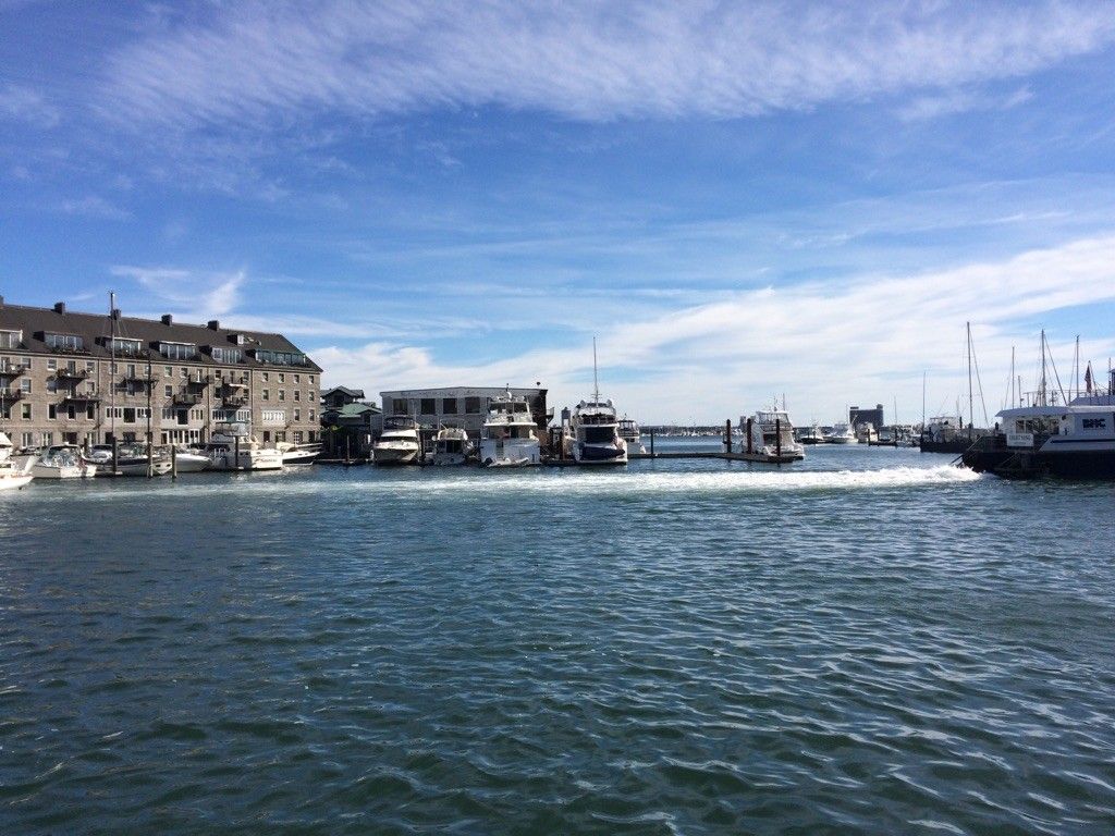 Boats docked in a harbor with buildings under a bright blue sky. - Walking City Trail Section 4