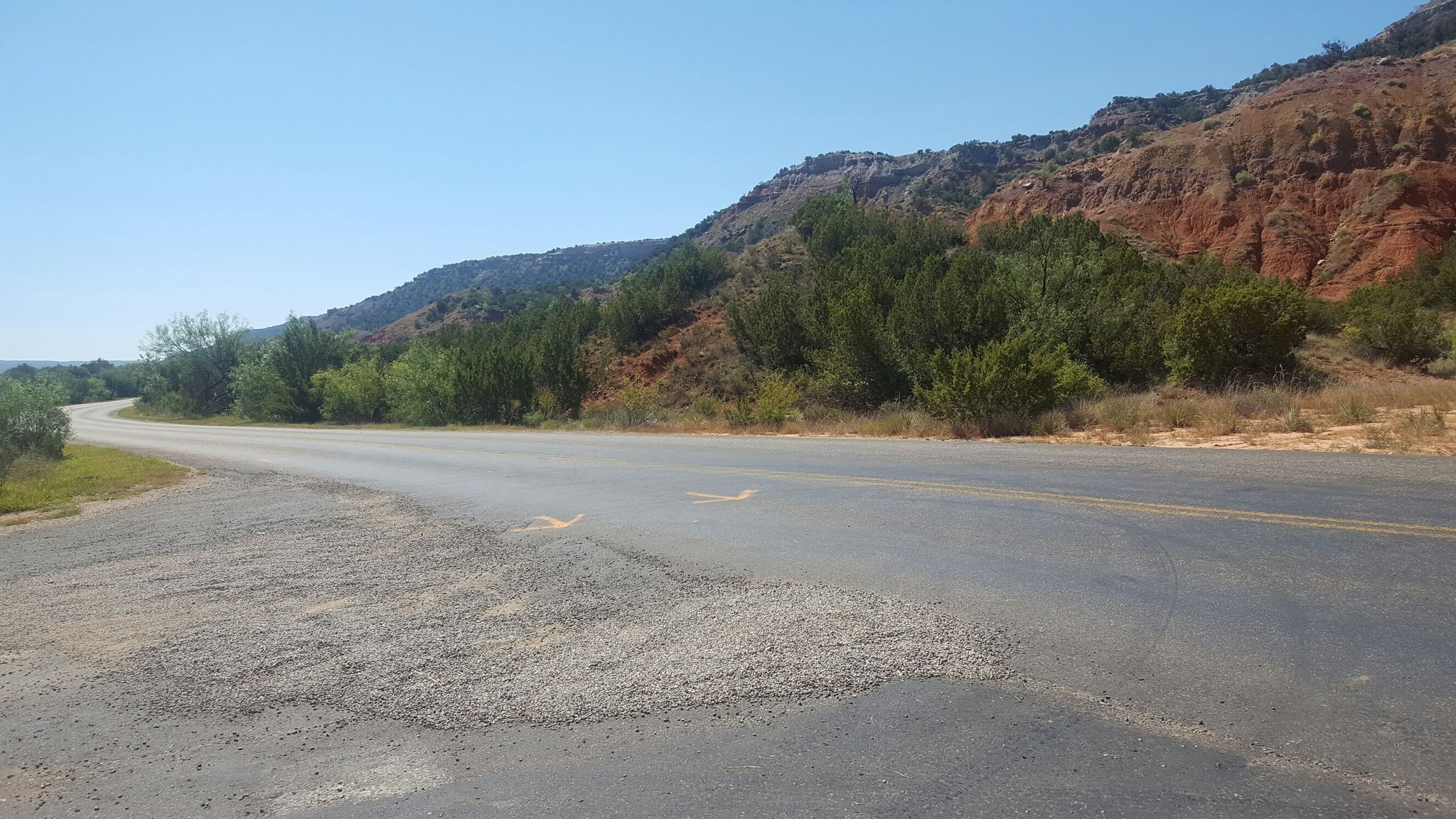 Paved road curving through a desert landscape with red hills. - Sunflower Trail – Lighthouse Peak Trailhead loop from Corral