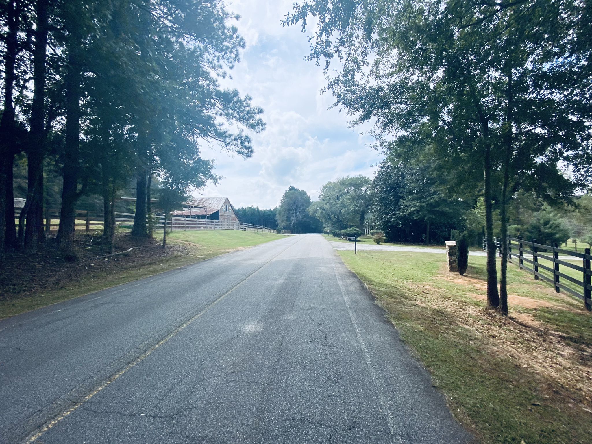 Paved road through a treelined landscape, with a barn visible in the distance. - Smith Grocery, Rico loop from Campbellton